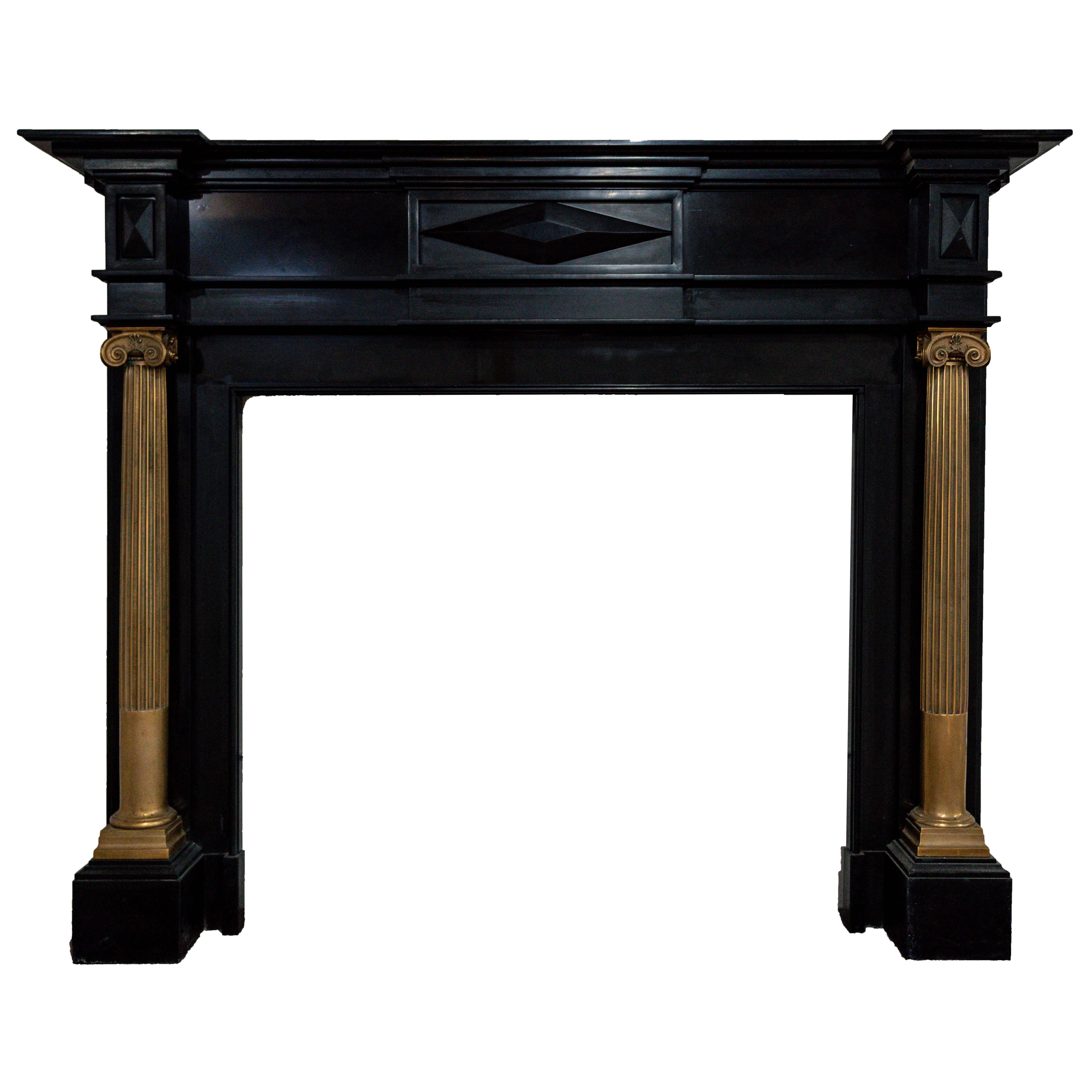 Un imponente camino inglese del periodo Regency realizzato in marmo nero belga, ornato da colonne scanalate in bronzo dorato e capitelli ionici. Risalente al 1820 circa, questo caminetto esemplifica la raffinata simmetria architettonica e gli