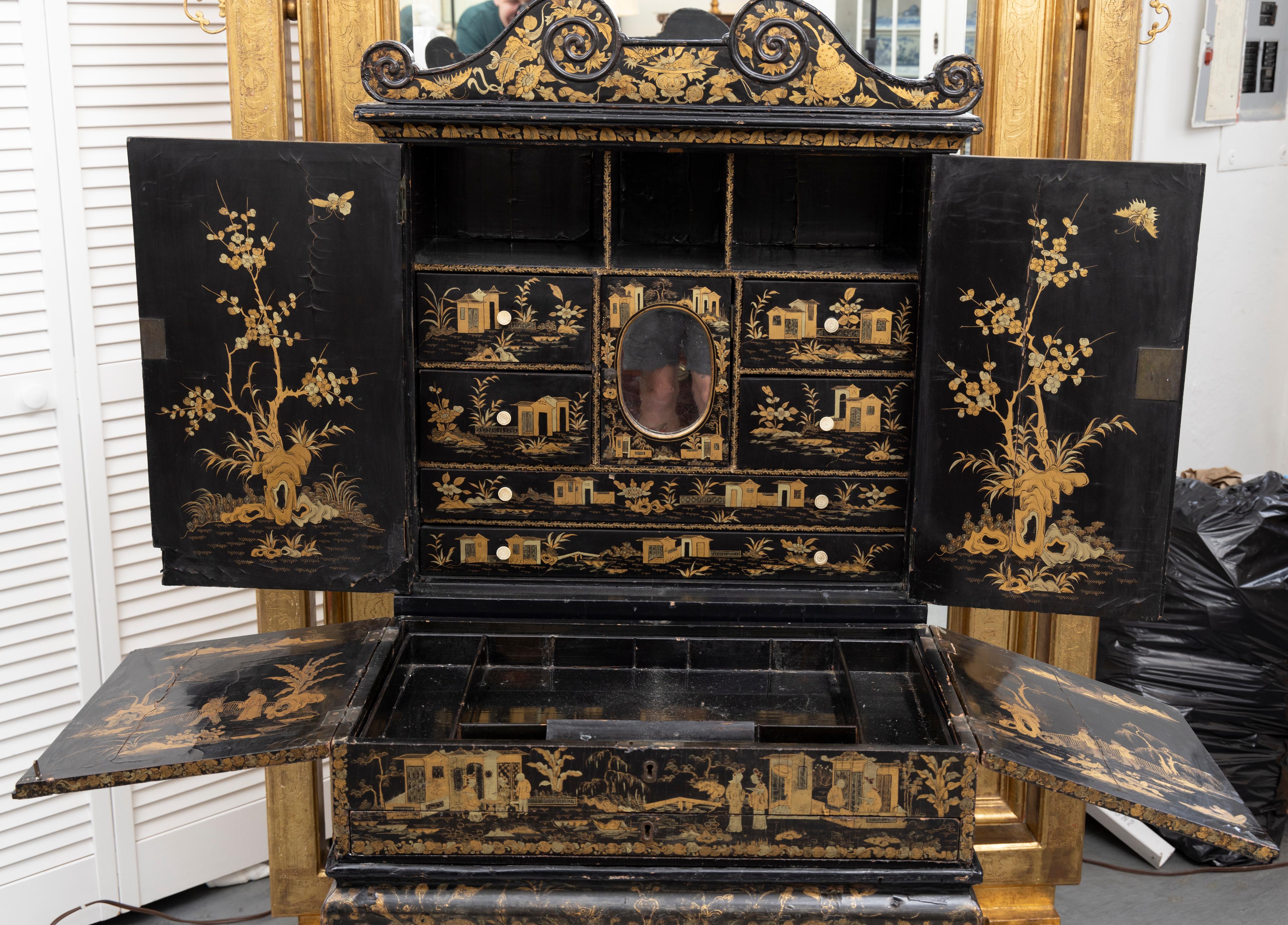 Il s'agit d'un cabinet décoratif Regency laqué noir très spécial, abondamment recouvert de chinoiseries dorées, représentant des motifs chinois. La structure physique du meuble présente un fronton bas en col de cygne au-dessus de deux portes qui