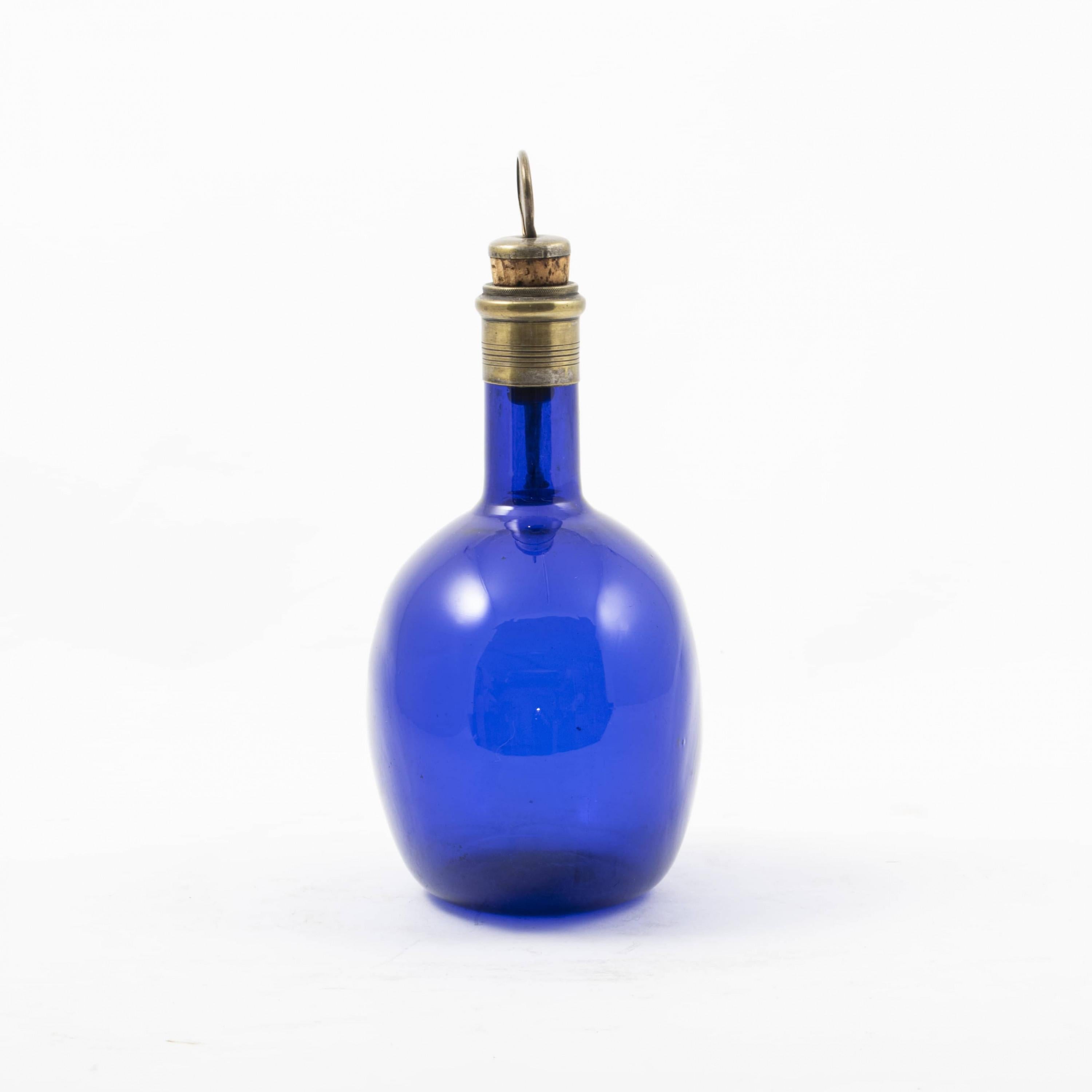 Small elegant regency cognac decanter.
Blue oval glass body with bronze neck and handle in the shape of a crane. Original stopper with mother-of-pearl 