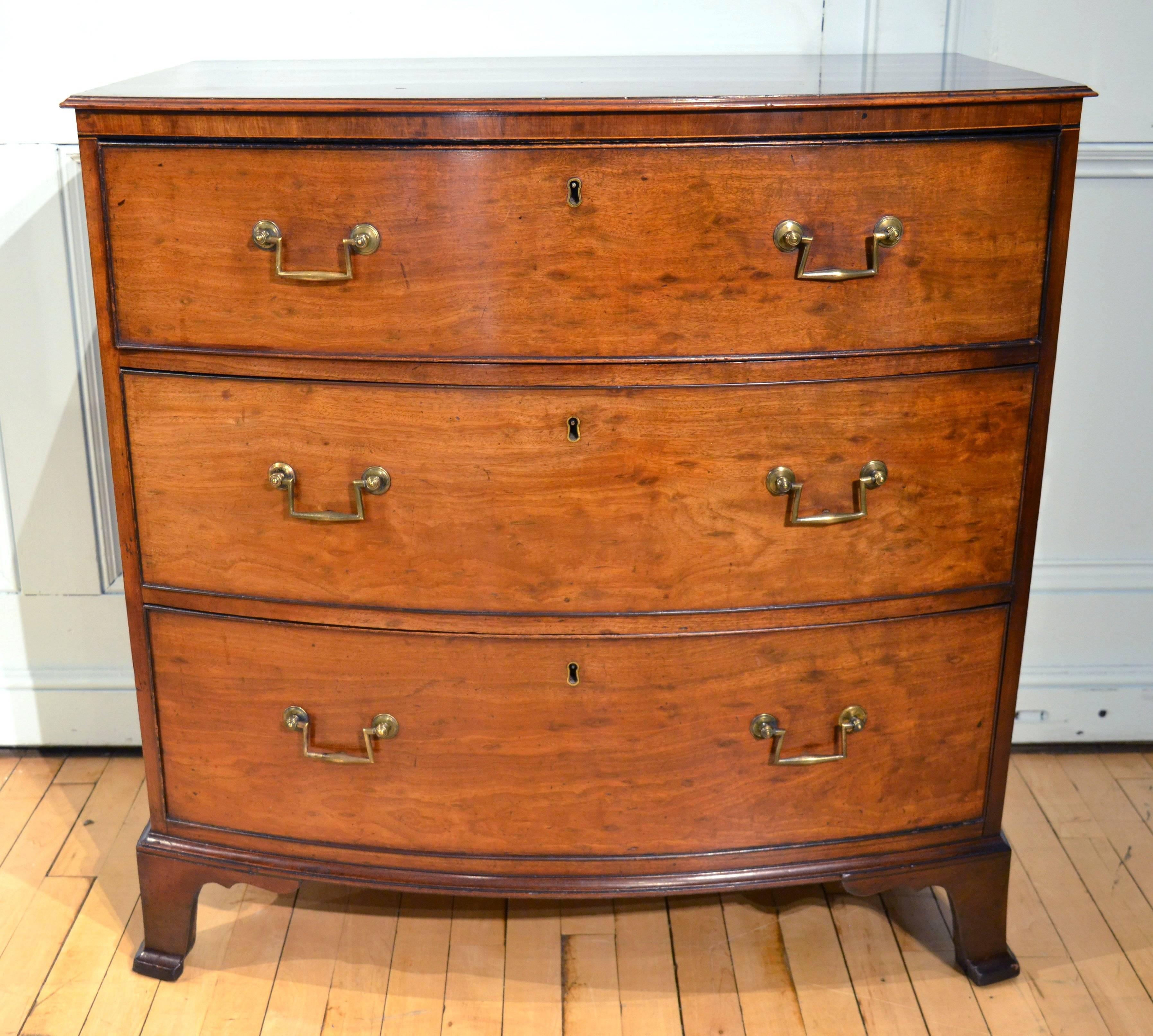 This handsome and excellent quality English Regency mahogany chest of drawers features a bow front design with ebony and boxwood stringing. The chest has three long, well-proportioned drawers with the original handles as well as locks and key. It