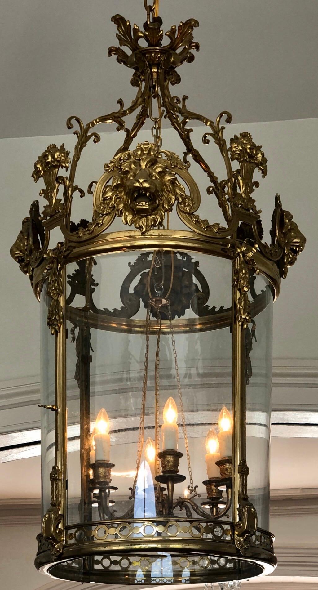 Monumentale englische Regency-Messinglaterne mit Löwenmaske wird von einem Interior Cluster mit sechs Kandelaberarmen beleuchtet, die ursprünglich Kerzen waren. Diese klassische Regency-Laterne hat vier gewölbte Glasvierecke (eines davon mit