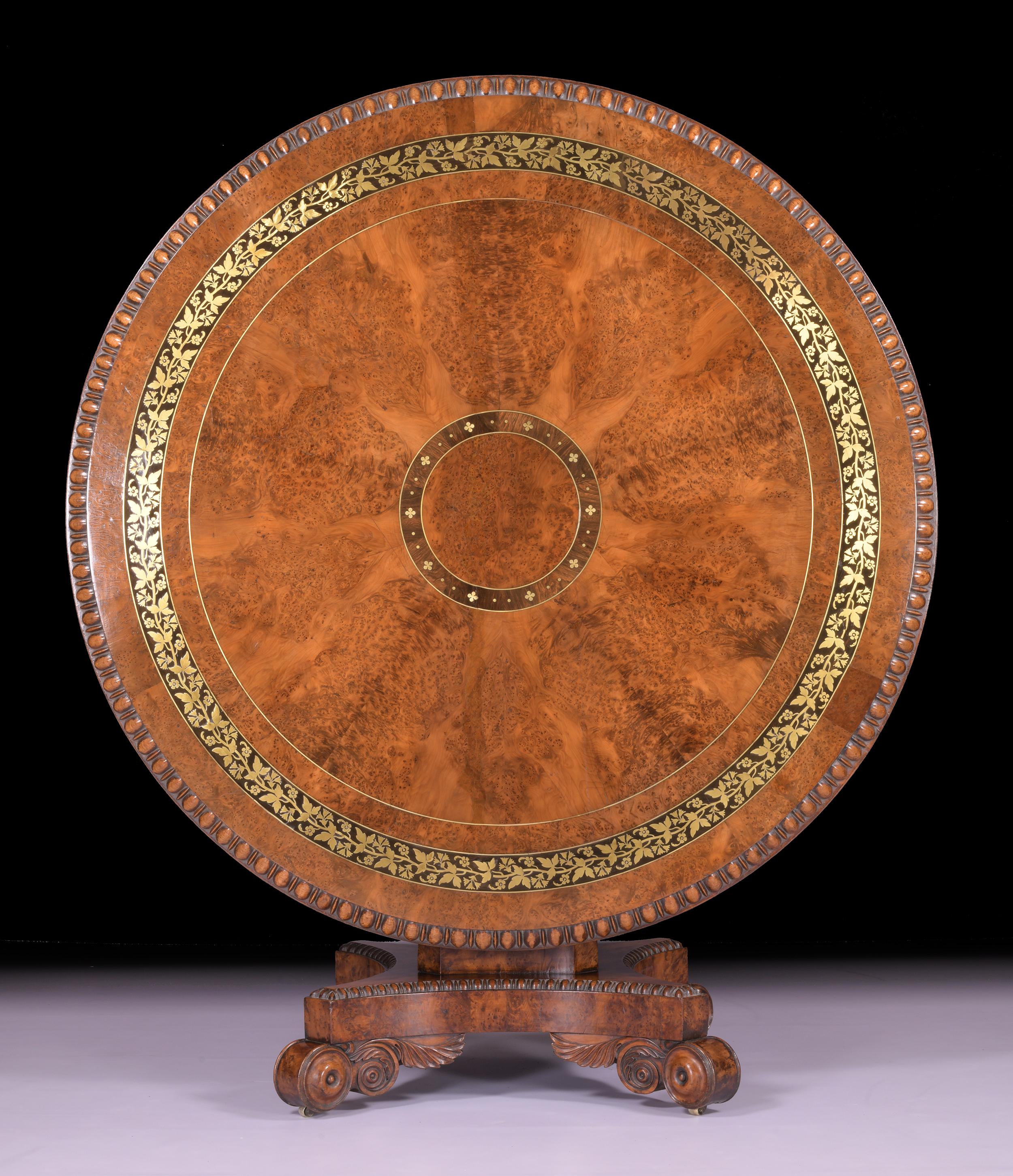 An exceptional Regency Burr Yew wood centre table attributed to George Bullock, the circular top having ebony strung segmented central panel and brass foliate scrolling floral marquetry band within a cross banded border with bead and reel carved