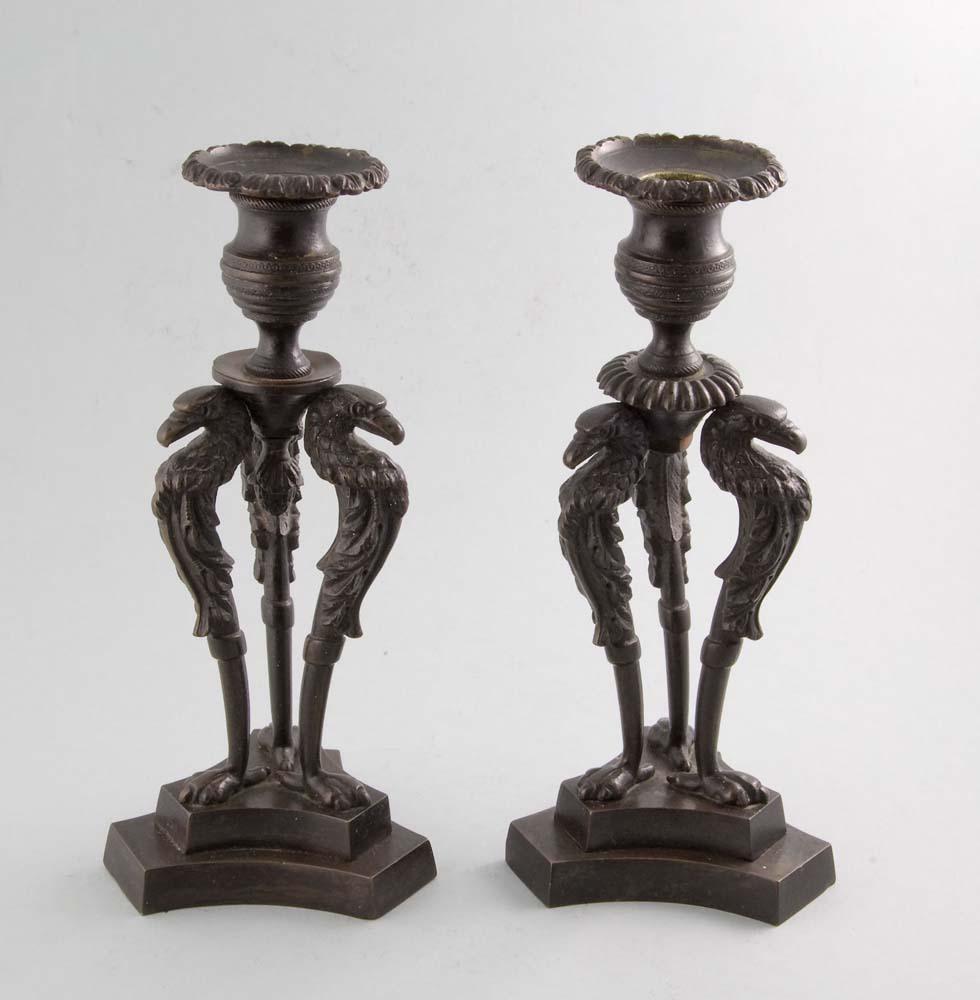 Une paire très fine et originale de chandeliers anglais de la fin de la Régence ou du George IV en bronze patiné. Posé sur une base triforme à gradins, le bougeoir est soutenu par trois aigles de la monedia. Le support du bougeoir est godronné et