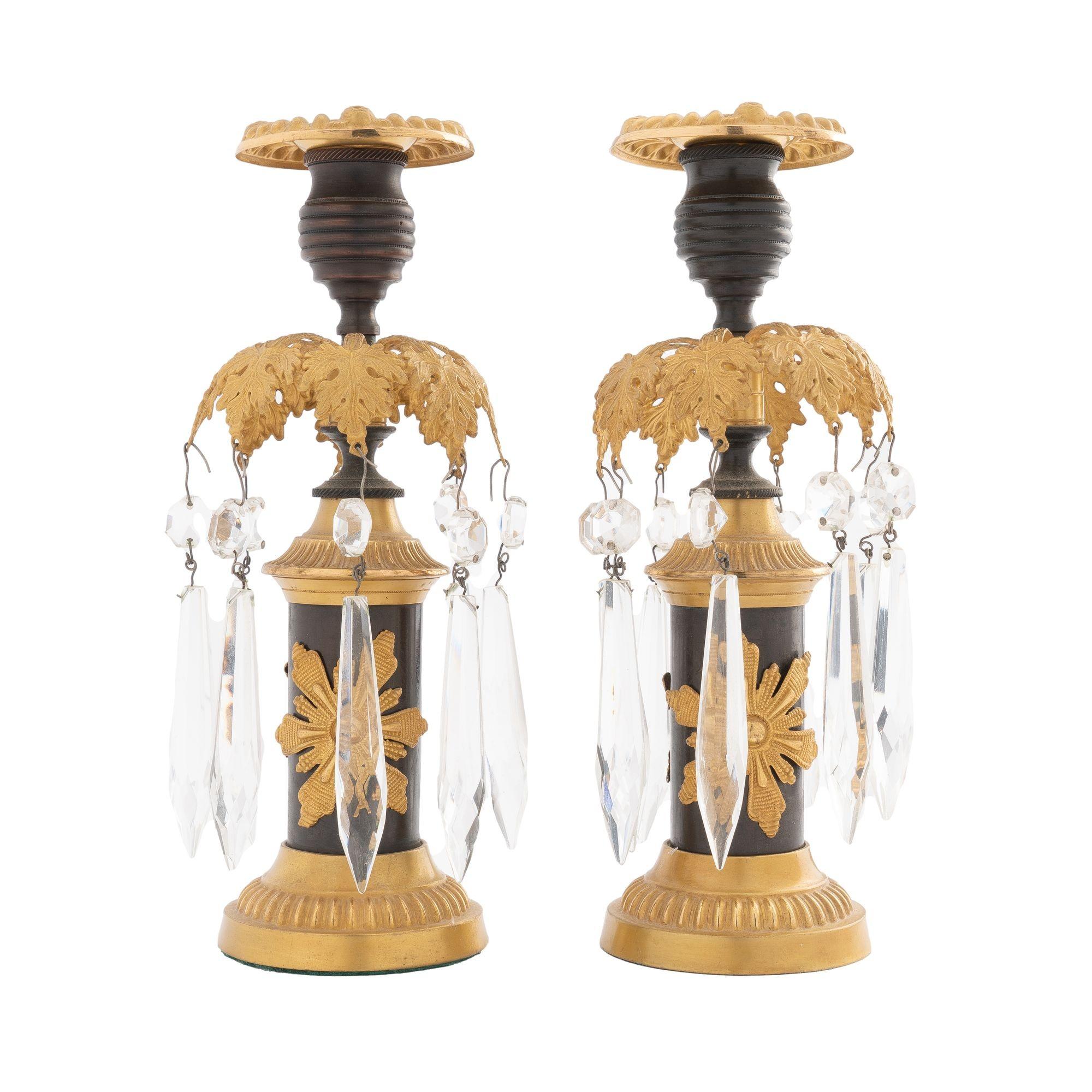 Pair of cast bronze patinated candlesticks with applied stamped & gilt lacquered brass embellishments. The foliate luster ring is hung with tear drop cut crystal lusters. These candlesticks are in excellent original condition and are very fine