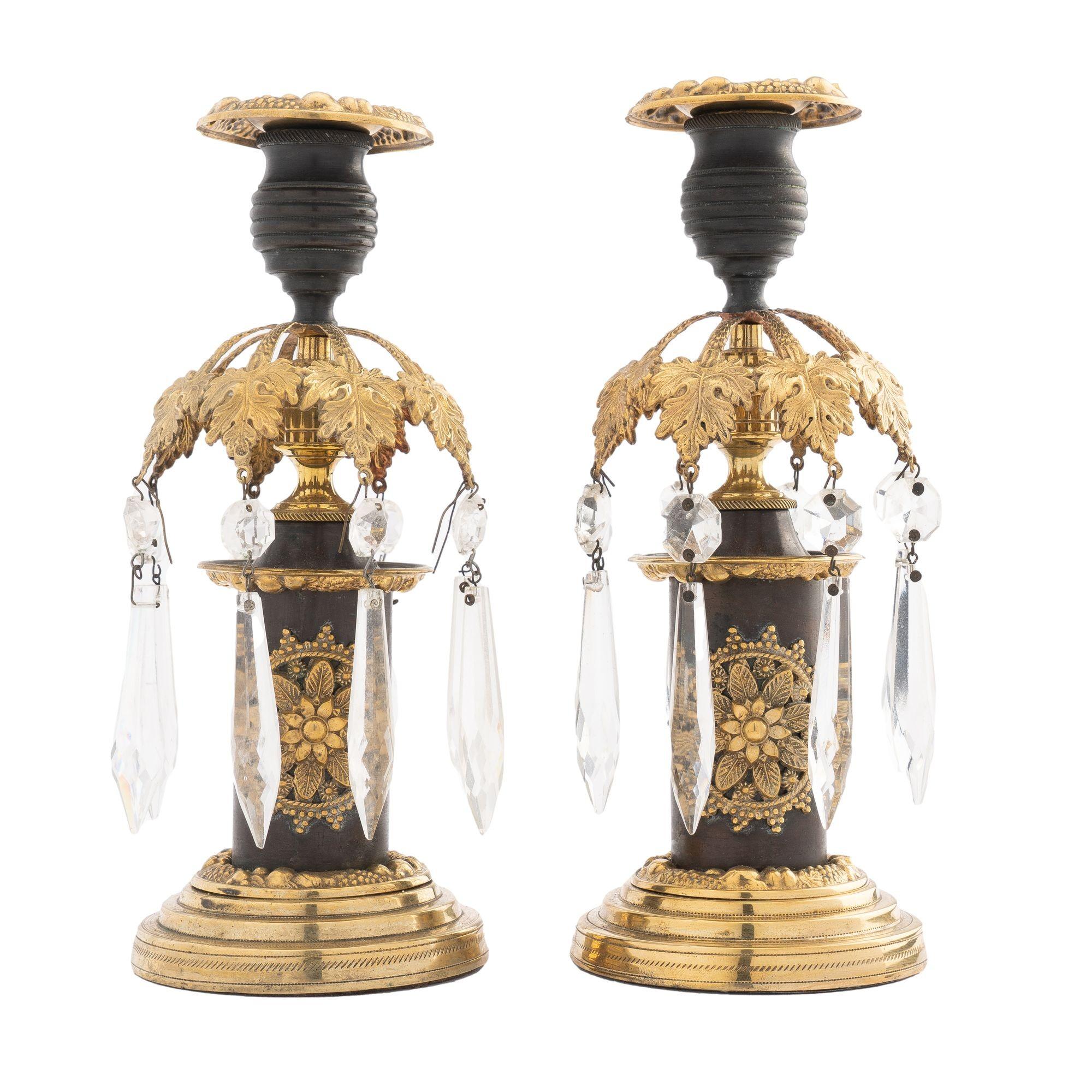 Pair of cast & patinated bronze candlesticks with applied stamped & polished brass embellishments and foliate luster ring. Hung with tear drop cut crystal lusters.

England, Regency Period, circa 1800.