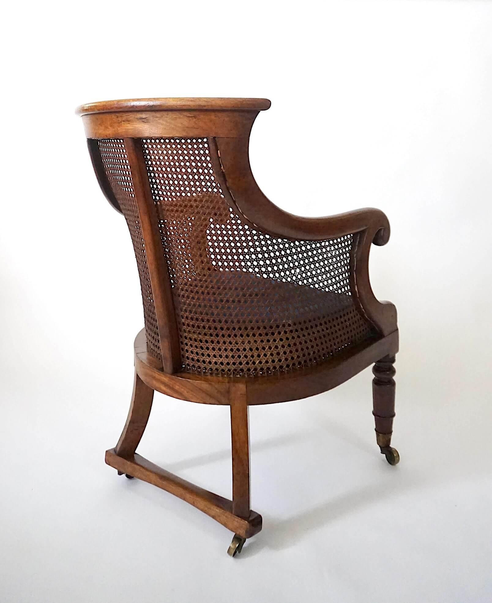 Intagliato a mano Poltrona o bergere di forma insolita in mogano, circa 1830, della Reggenza inglese, con canne. in vendita