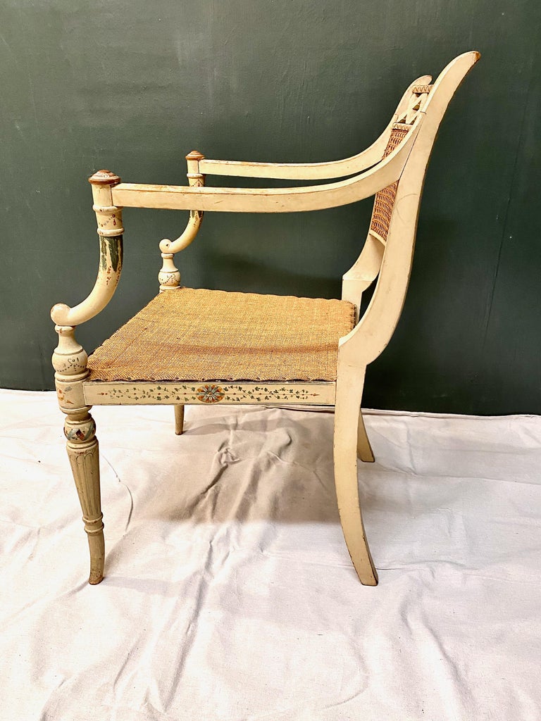 This is a very decorative early 19th century English Regency open arm chair that retains its original painted surface. The seat caning has an old burlap replacement; the back retains its original cane. I love the deep natural patina of this