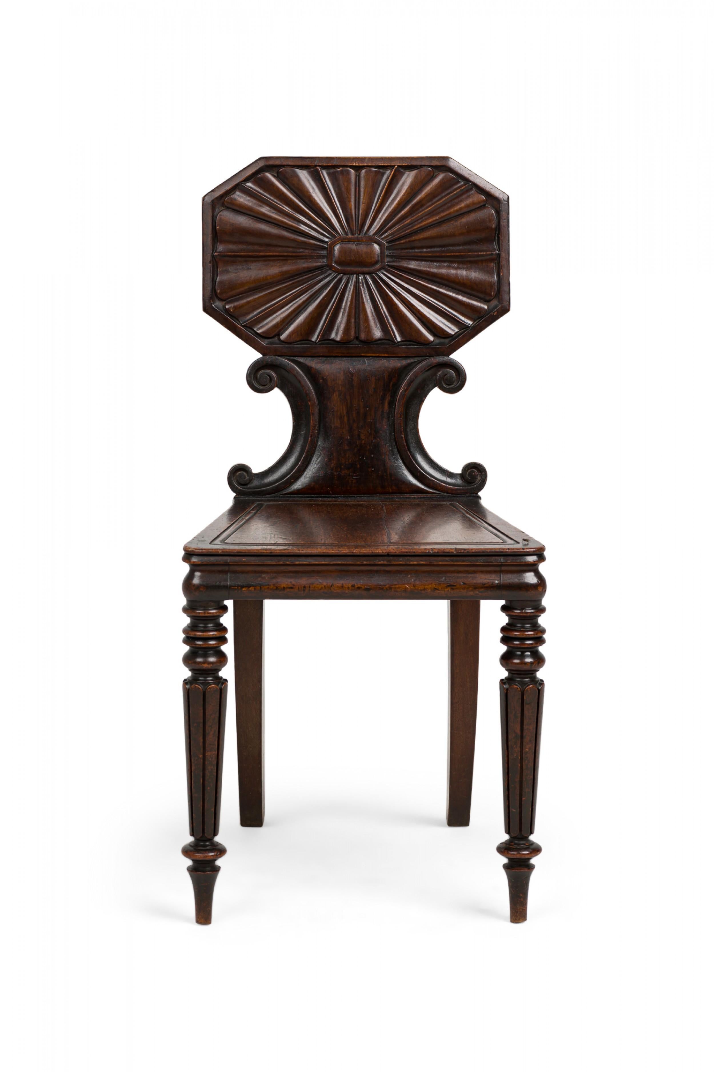 PAIR of English Regency (early 19th Century) mahogany hall / side chairs with an octagonal back upper section displaying a handcarved radiating cartouche anchored by a scrolled concave bottom, with rounded trapezoidal seat with inset borders,