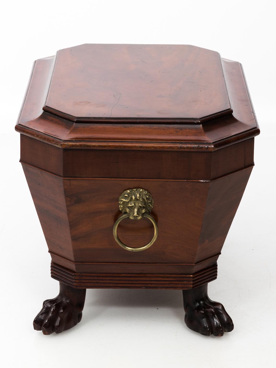 English Regency style cellaret in mahogany with recently replaced fauxwood liner, circa 1820s-1830s. The box is highlighted with original brass hardware and carved lion's paw feet. There is also wear with age as seen with surface scratches on the