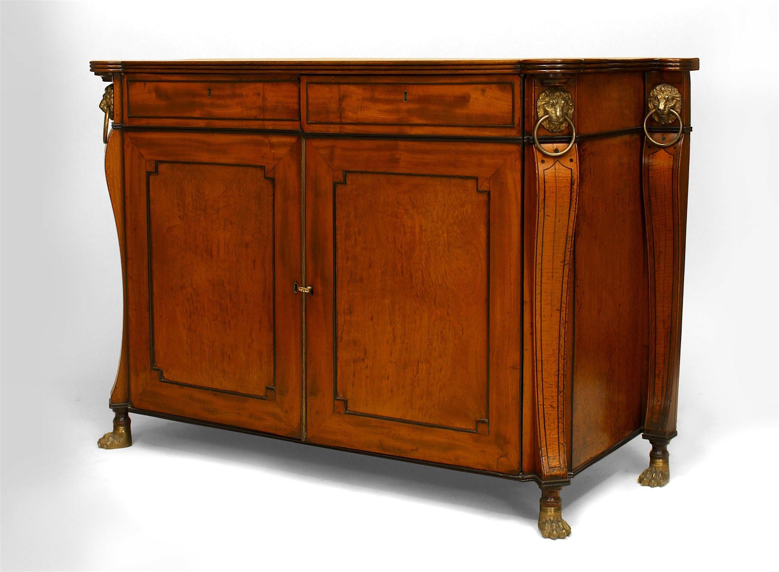 English Regency mahogany and ebonized trimmed commode with flaired back sides and 2 drawers over 2 large doors trimmed with bronze lion heads and claw feet.
