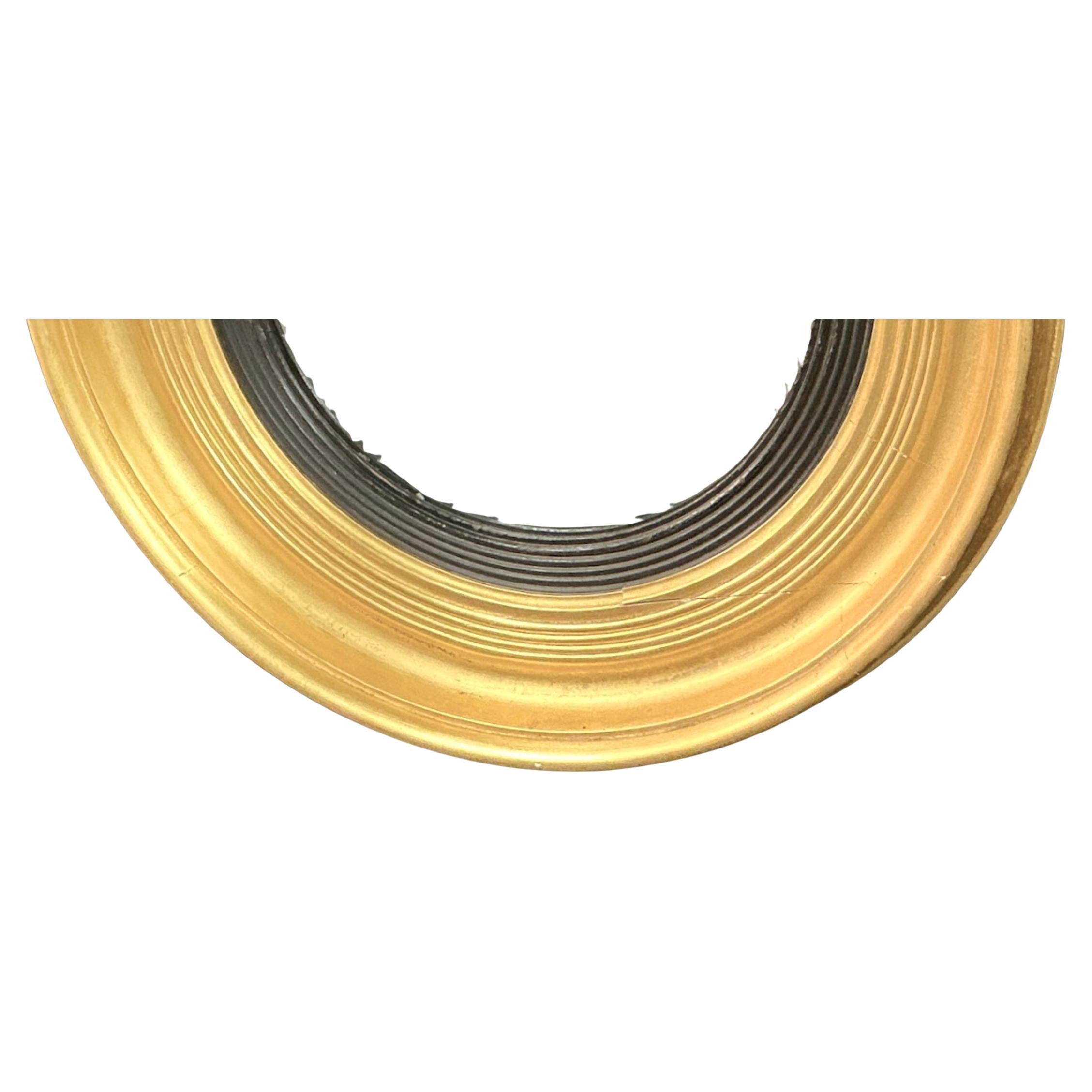 Miroir convexe en bois doré sculpté du début du 19e siècle. Le miroir présente un cadre circulaire avec un profil classique à cannelures, doré à chaud, avec un revêtement intérieur noir contrastant, accentuant la convexité du verre. Le verre convexe
