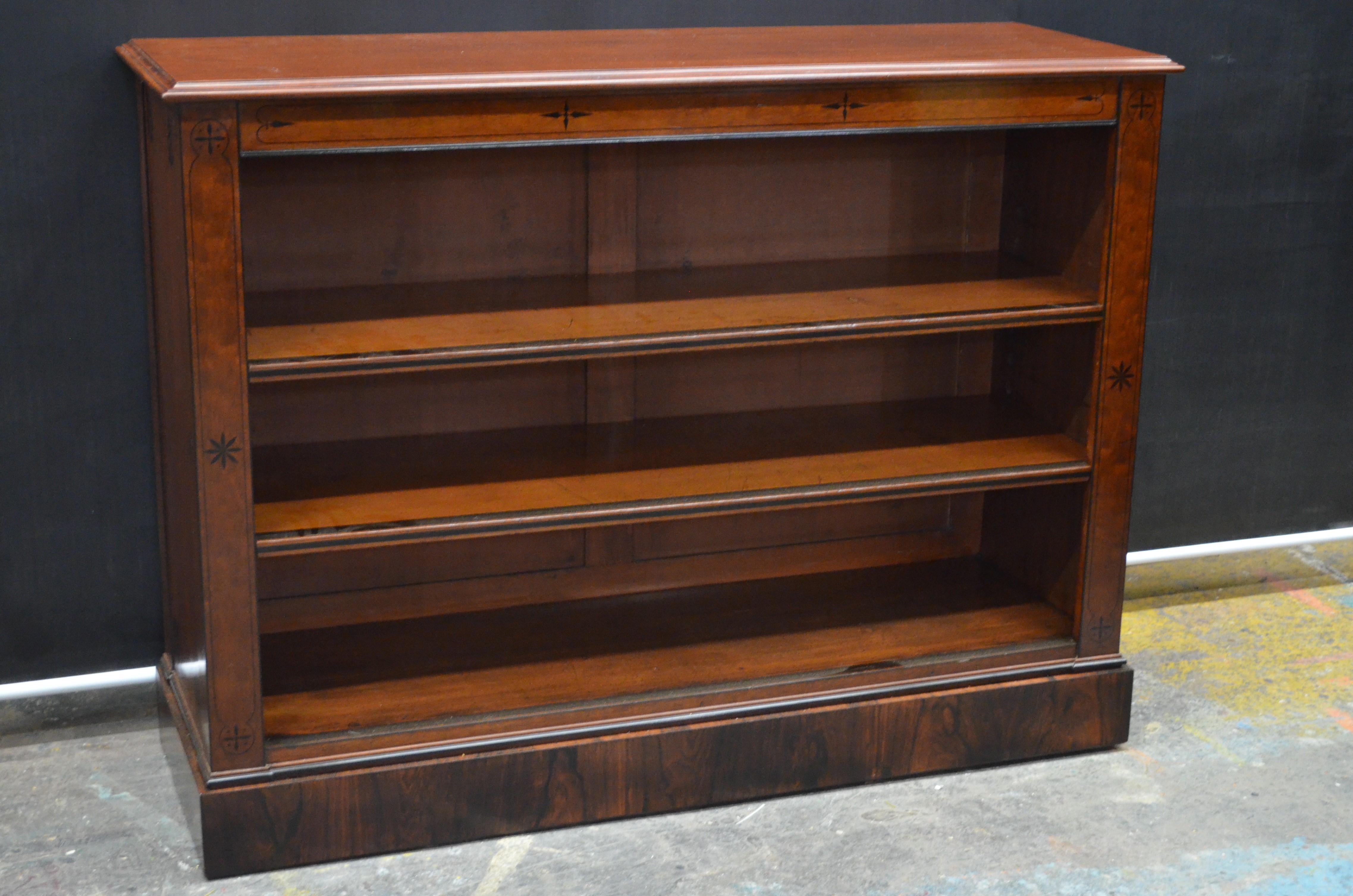A Regal English Regency Ebony Inlaid mahogany open shelf bookcase made in the early 19th Century. This Regency Egyptian Revival Bookshelf has a Solid Mahogany Top with concave step molded edge. The Mahogany Top is above a Solid Mahogany Frieze with