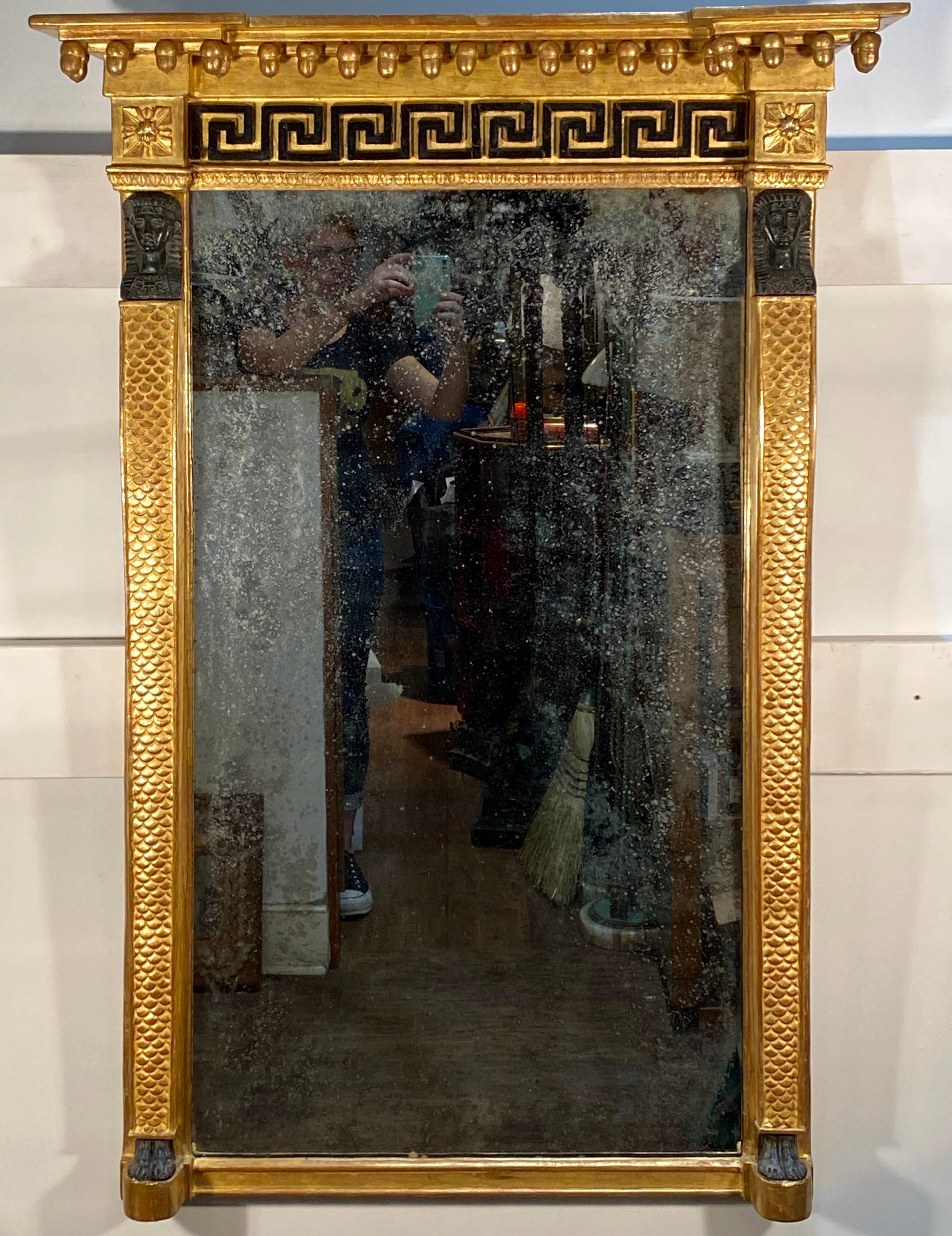 This English mirror shows all of the elegant grandeur of the Regency period by combining Egyptian and Greek motifs. The mummies are exquisitely executed on the caryatid figures with fish scales motif. The pier mirror has an overhanging cornice with