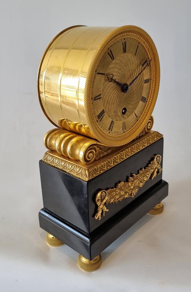English Regency ormolu and Derbyshire black marble mantel clock. Typical drum shaped clock, set on four elaborate ormolu toupee feet. The Derbyshire black marble base has an applied ormolu mount of flowers and fruit to the front. The ormolu drum