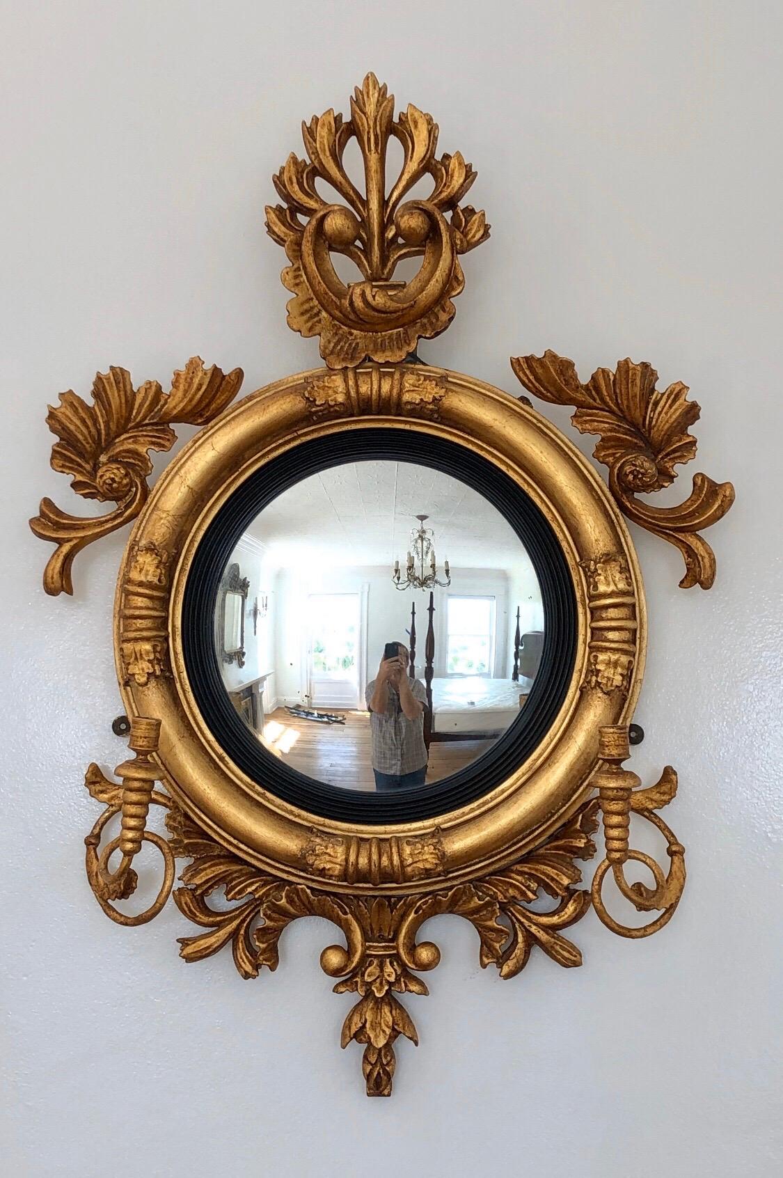 This Regal early 19th century British Convex mirror is craved gilt carved wood with Girandole candle arms.