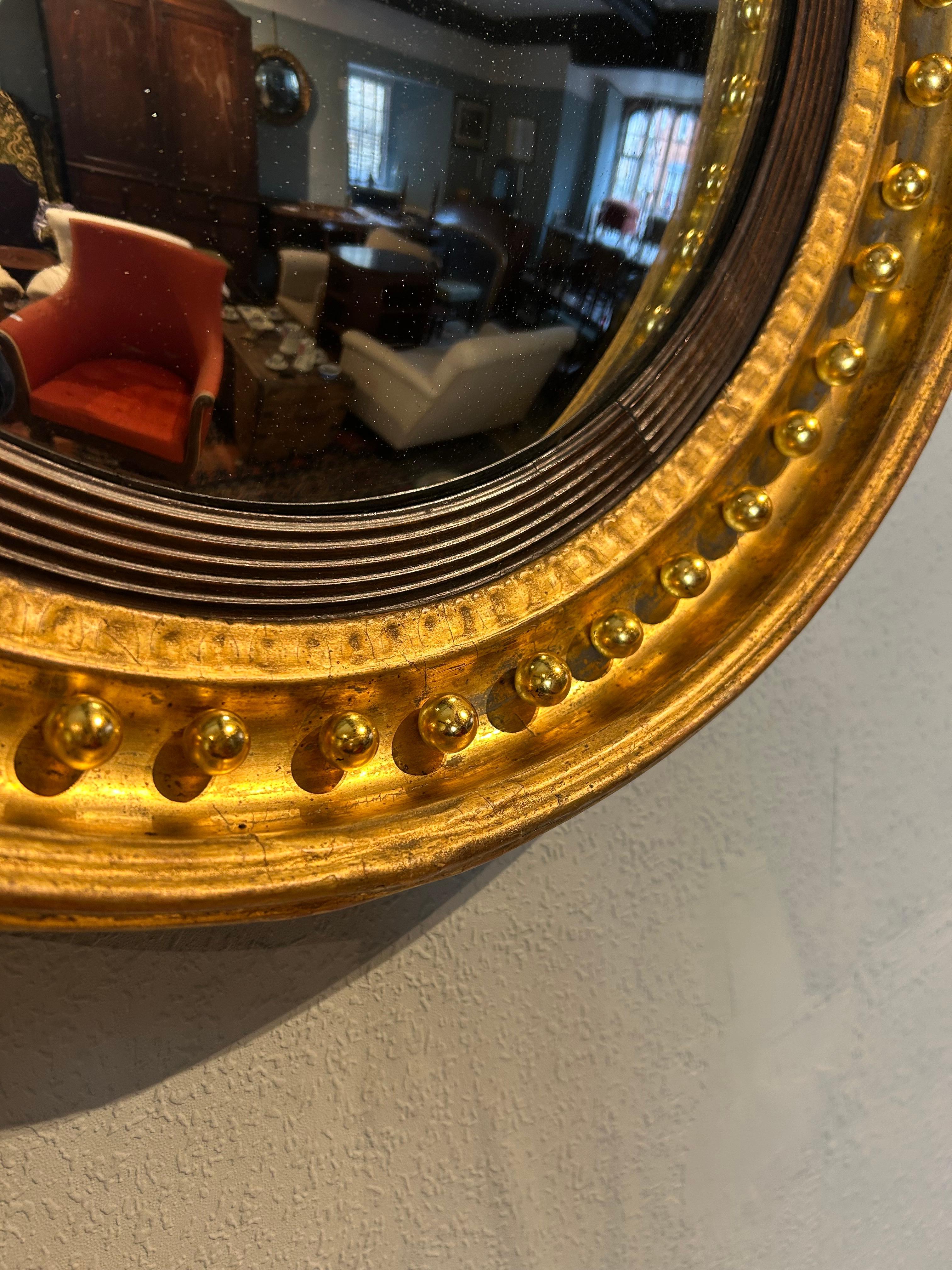 Regency convex mirror circa 1815 with slightly worn through water gilding and original mercury glass which is in very good condition, the pine back panel has its original maker’s paper label.