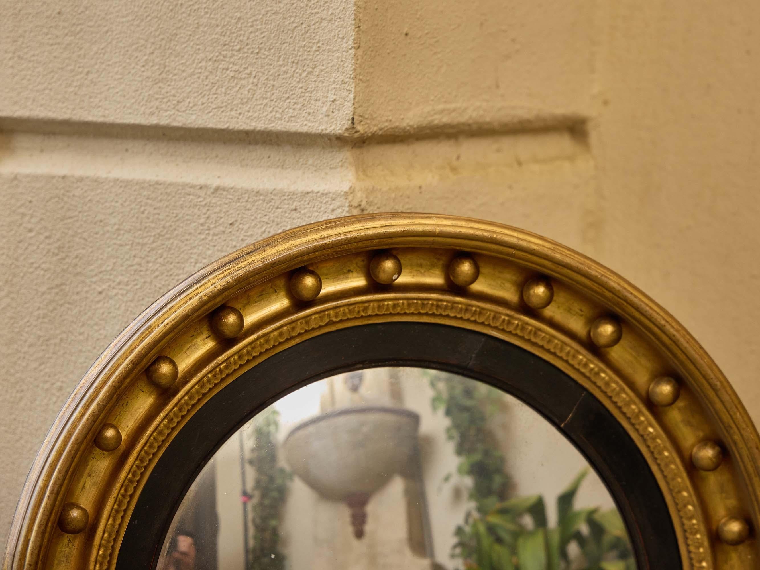 Intagliato Specchio convesso in legno dorato inglese Regency con finiture ebanizzate, XIX secolo in vendita