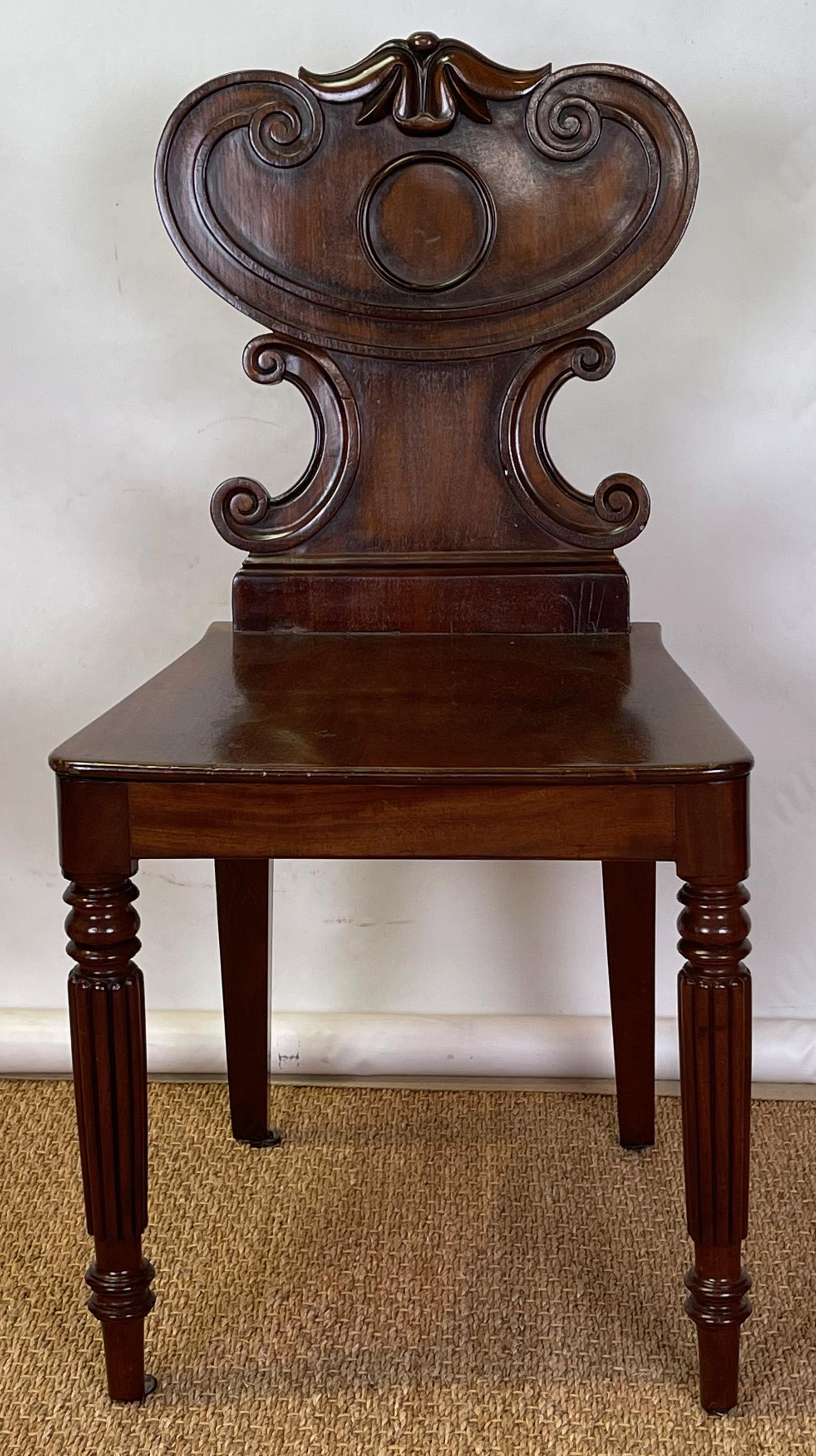 An early 19th C. English mahogany hall chair with cartouche shaped back resting on round reeded legs.
