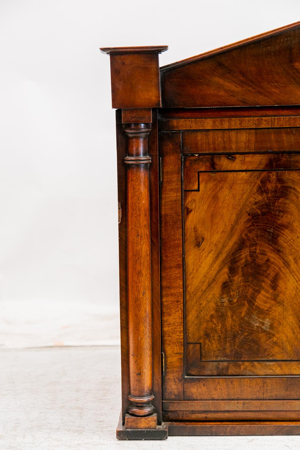 Die Türen dieses Regal-/Hängeschranks aus englischem Mahagoni sind mit Mahagoni umrahmt und haben vertiefte Paneele, die mit Ebenholzleisten ausgekleidet sind. Die Einlage aus Ebenholz umgibt das Mahagoni mit Flammenmaserung in Buchform. Die