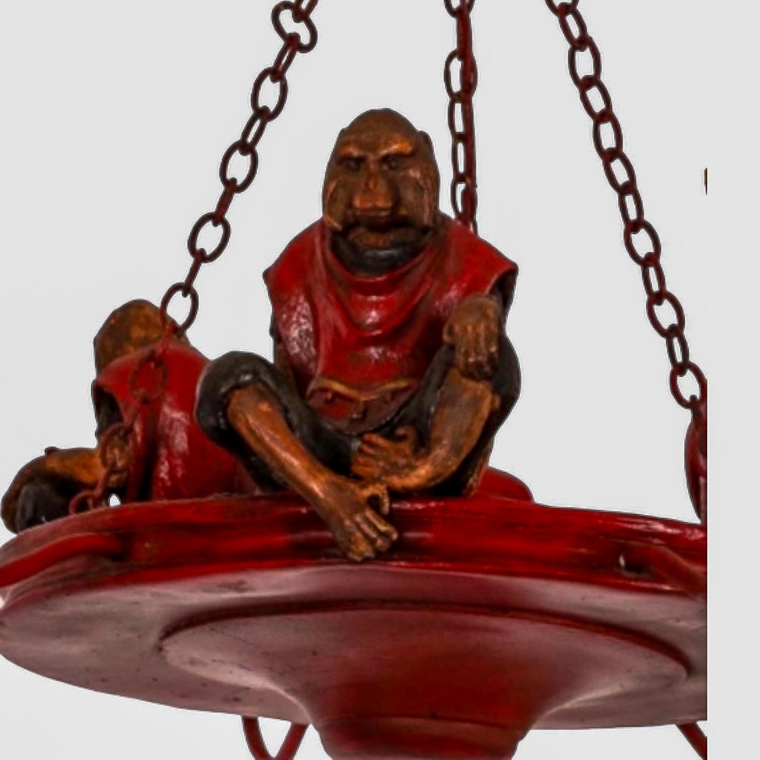 This is an English regency style hunt themed tole chandelier that depicts 3 seated monkeys dressed in formal wear. It is attributed to the artist Bill Huebbe. The piece dates to the 1980s and is in working order.