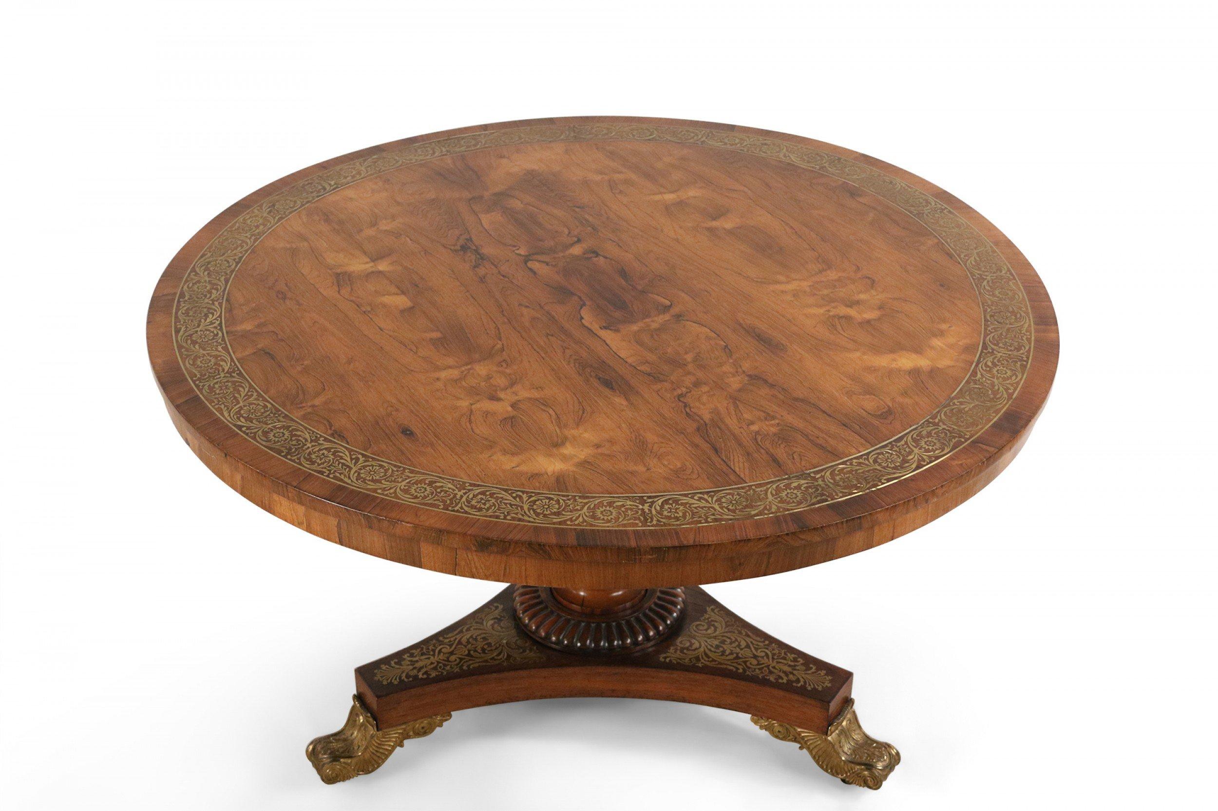 English Regency circular brass inlaid tilt-top center table resting on a turned & fluted trim pedestal over a triangular brass inlaid base supported on 3 gilt bronze shaped feet.