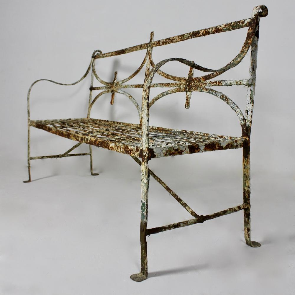 A truly wonderful and rare Regency English iron garden bench dating from circa 1830. Of unusual design and standing on penny feet, the whole retaining many layers of ancient paint, all beautifully weathered and worn

English, circa 1830.