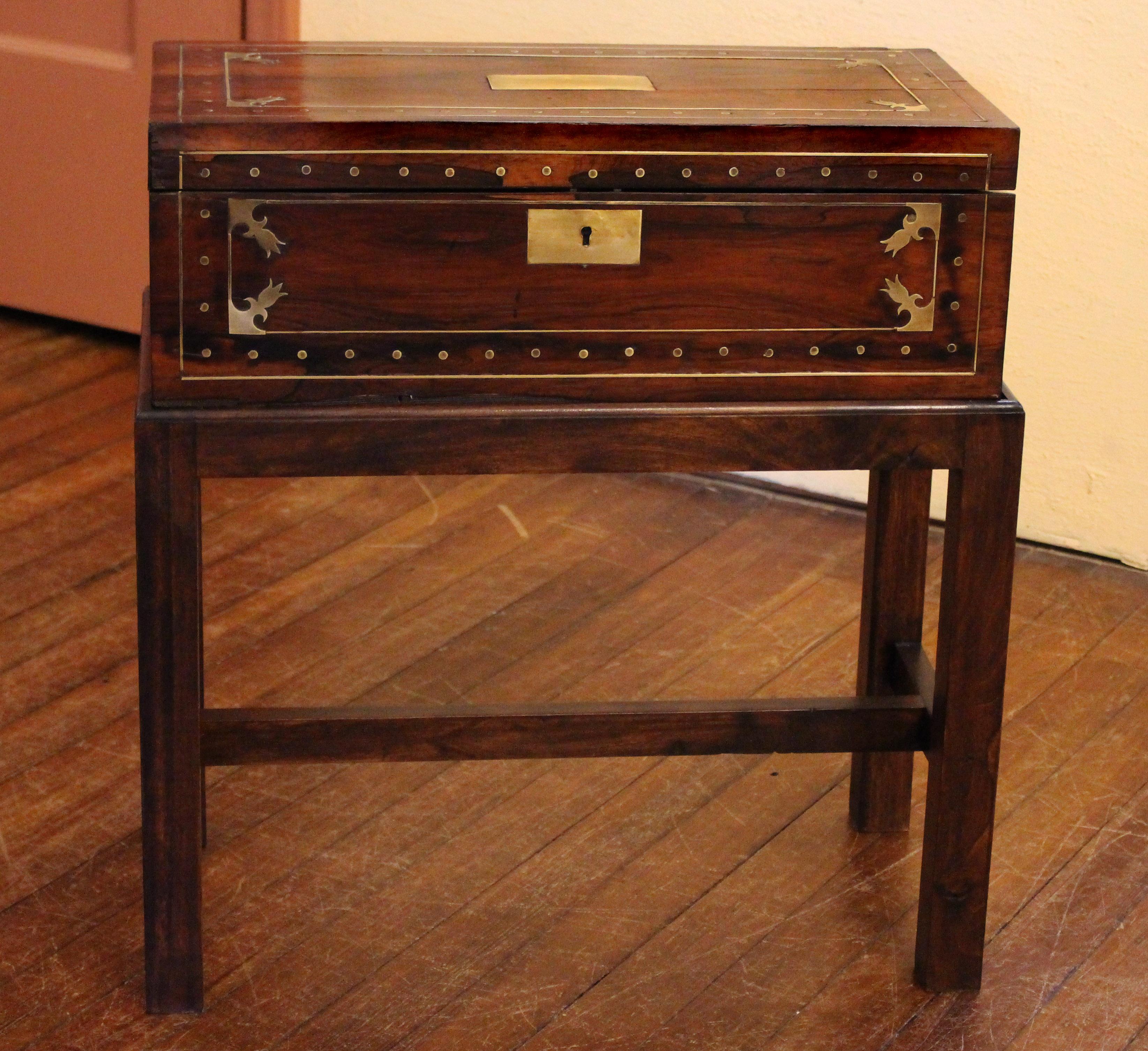 Early 19th century Regency lap desk now on custom made stand as a side table. English. Rosewood with extensive bold brass inlays. Various, though unobtrusive veneer losses commensurate with age & use. The interior surface re-baized. Secret interior