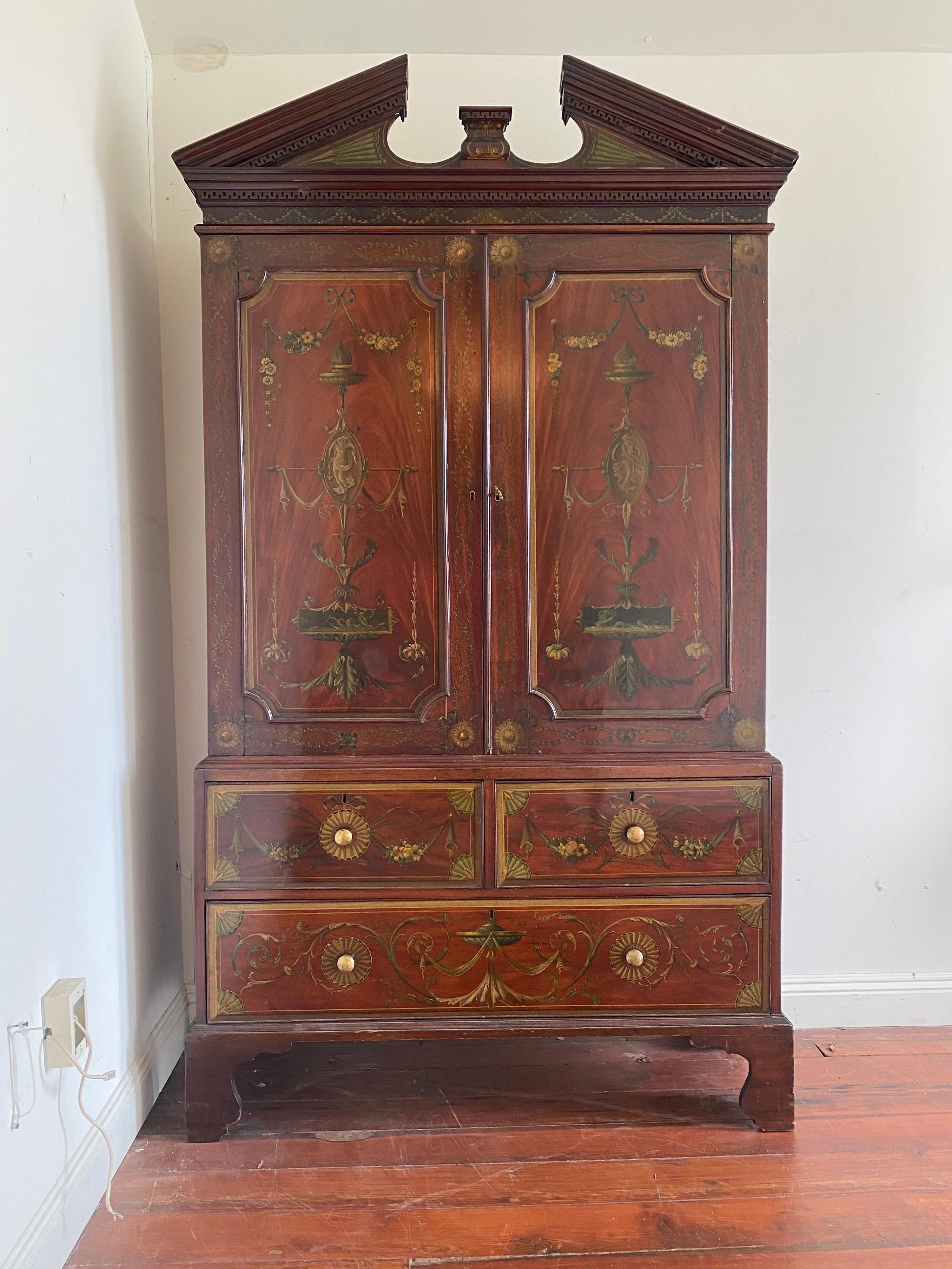 English Regency linen press with Adams style painted decoration. Two doors over two drawers. Broken pediment crown and ogre bracket feet. Silk lined on upper cabinet and paper lined drawers.