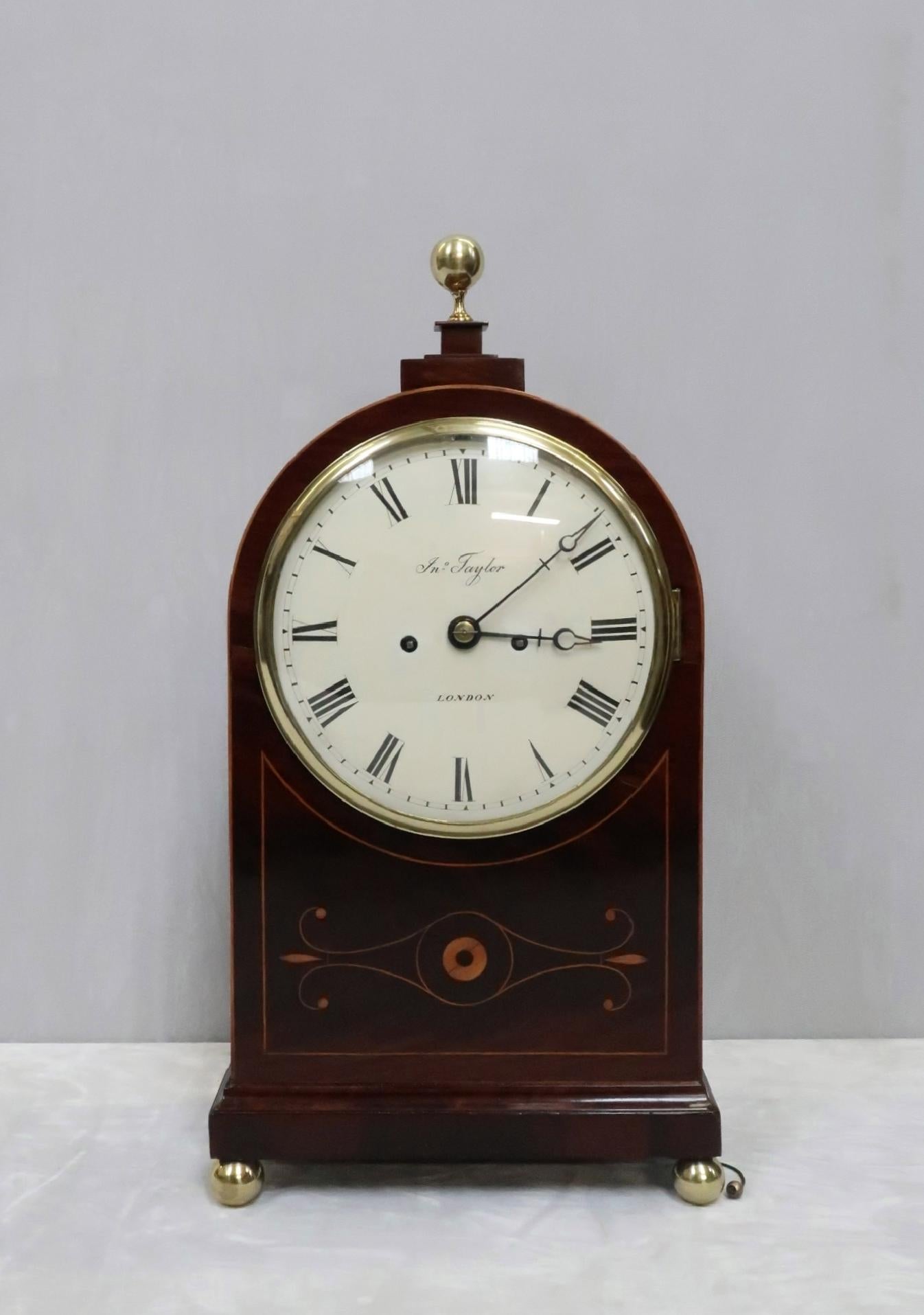 An extremely fine quality arched top mahogany English bracket or table clock with figured mahogany and boxwood string inlay to the front of the case and brass fish scale side sound frets.

The clock has an eight inch painted dish dial with the