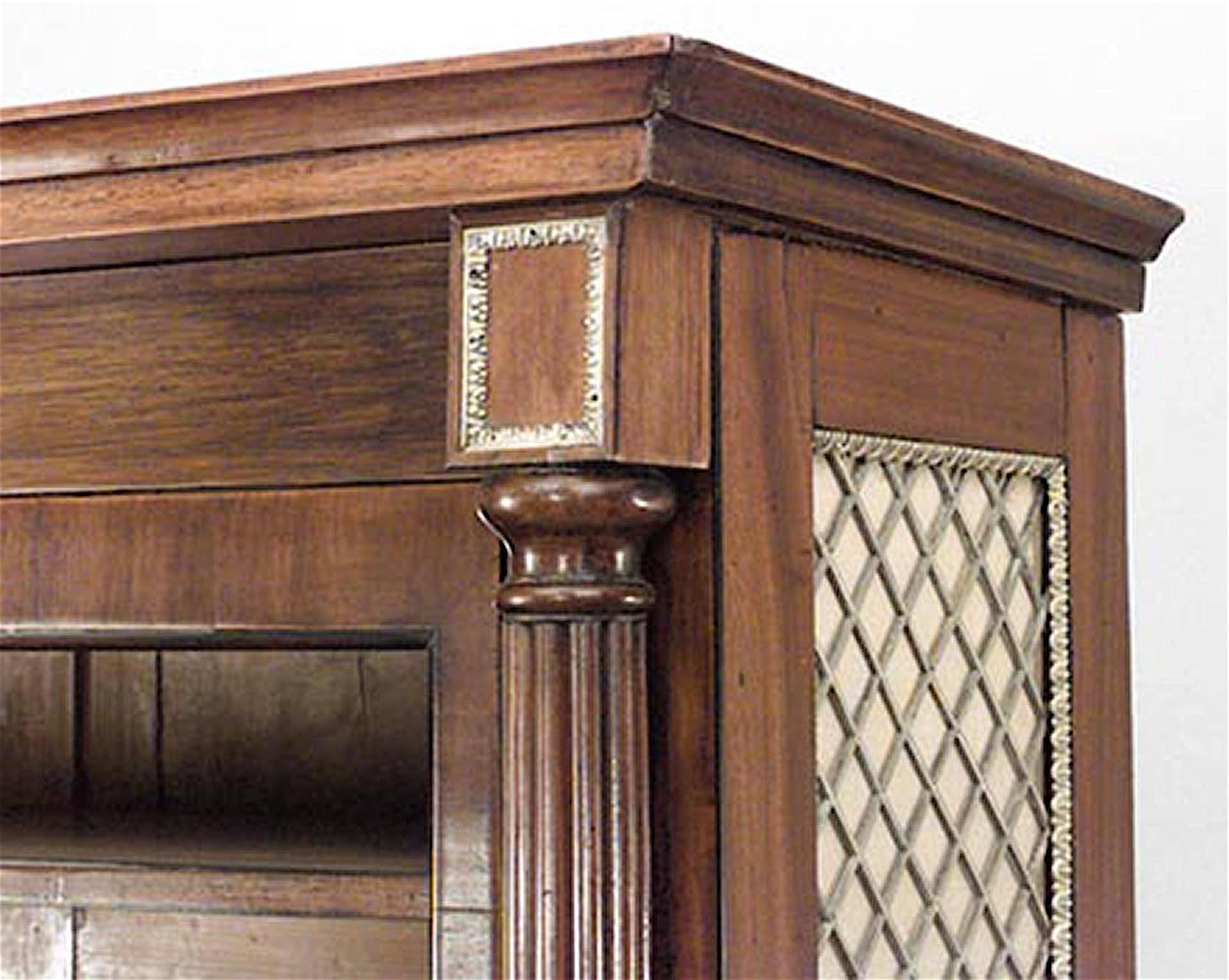 English Regency (Early 19th Century) mahogany bookcase with reeded columnar angles flanking glazed doors over green silk lined brass grilled doors on lions paw feet. (Manner of Gillows)
