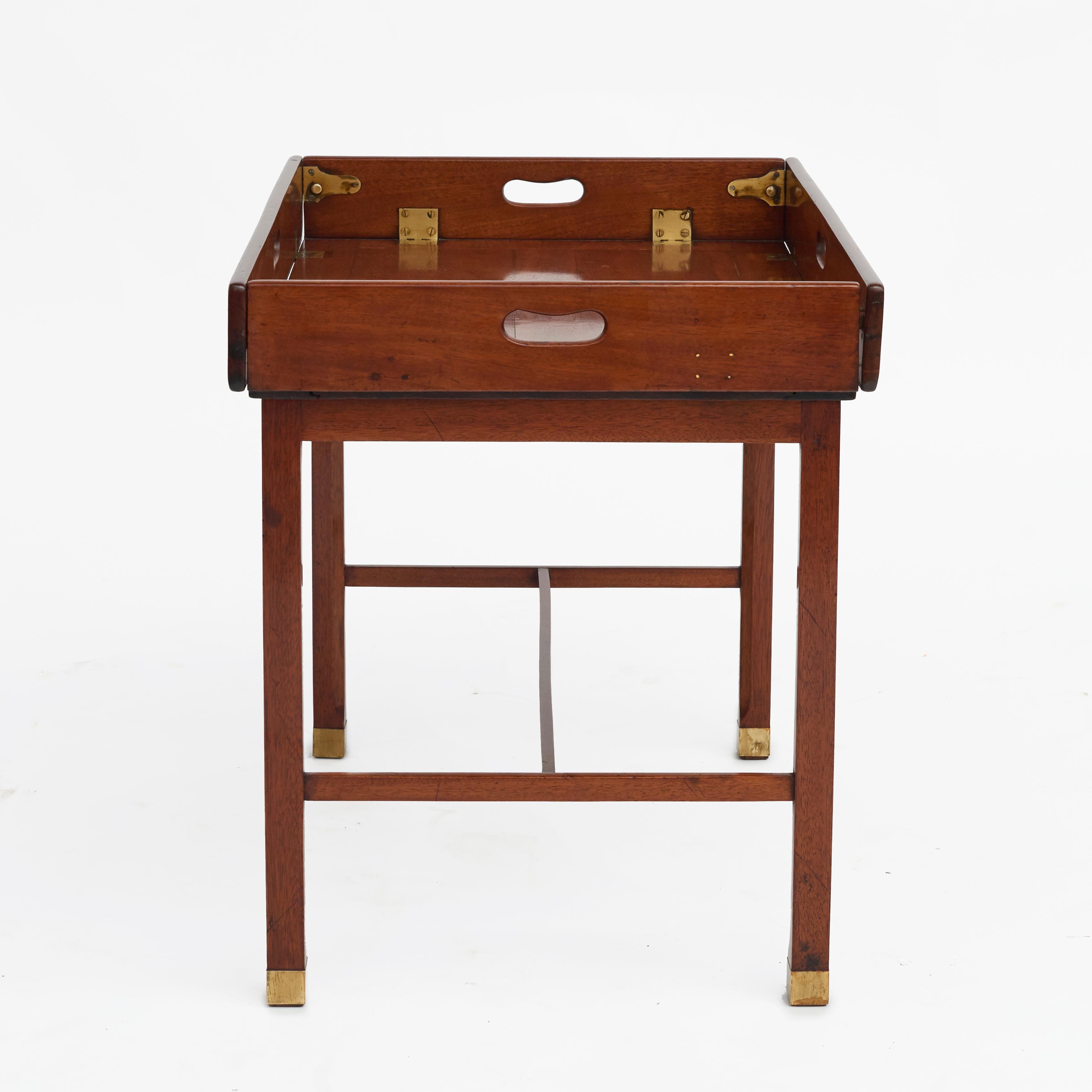 Early 19th century English regency period butler's tray in mahogany with original brass hinges.
Pierced handles to all four folding sides, housed on later square leg mahogany stand ending in brass shoes.

England 1810-1820.