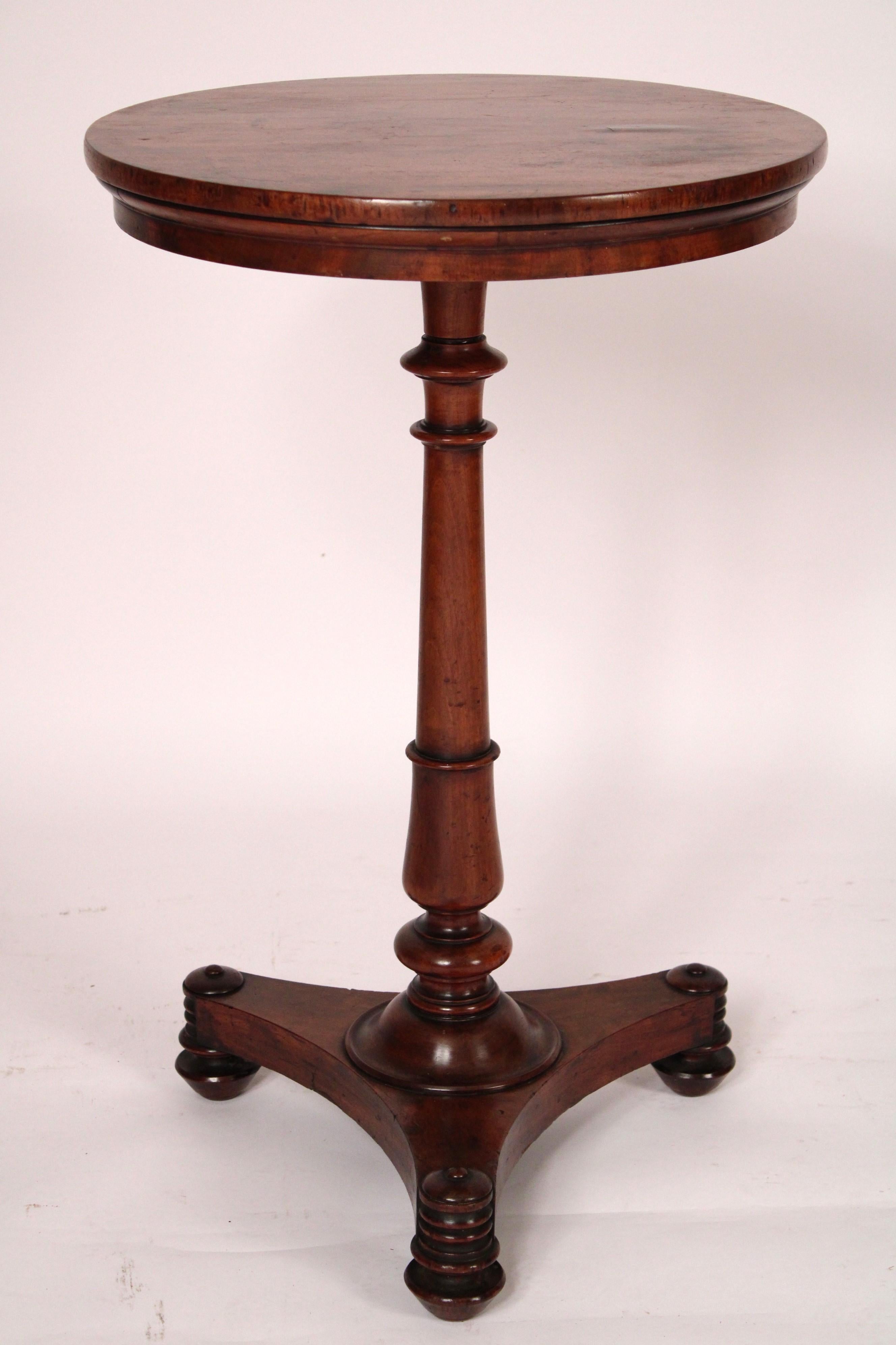 English regency mahogany candlestand / occasional table, circa 1820. With a circular top an elongated vase shaped pedestal resting on a trefid base with beehive corners, resting on turned tapered feet. With an excellent old patina. The bottom of the