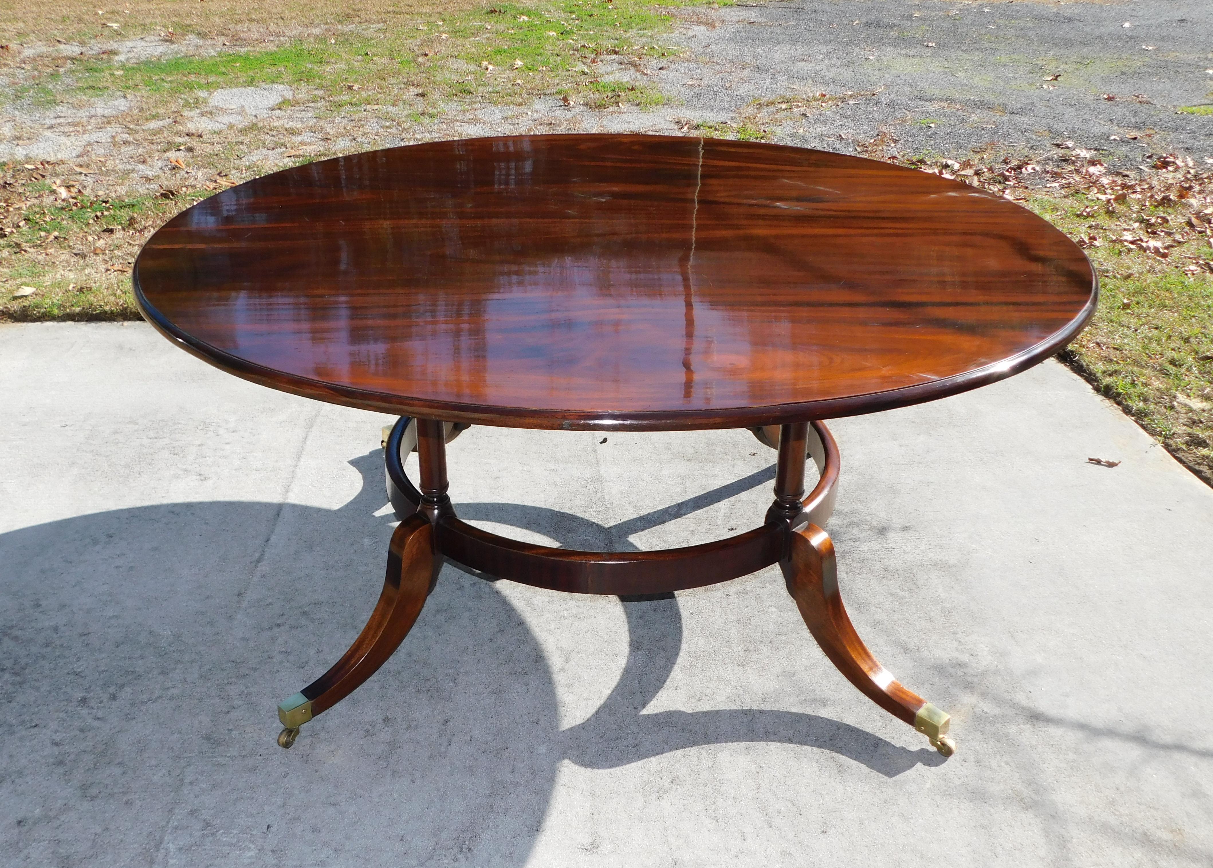 English Regency Mahogany circular dining room table with turned ringed support columns, lower circular skirt, and resting on splayed legs with the original brass casters. Mid 19th century.