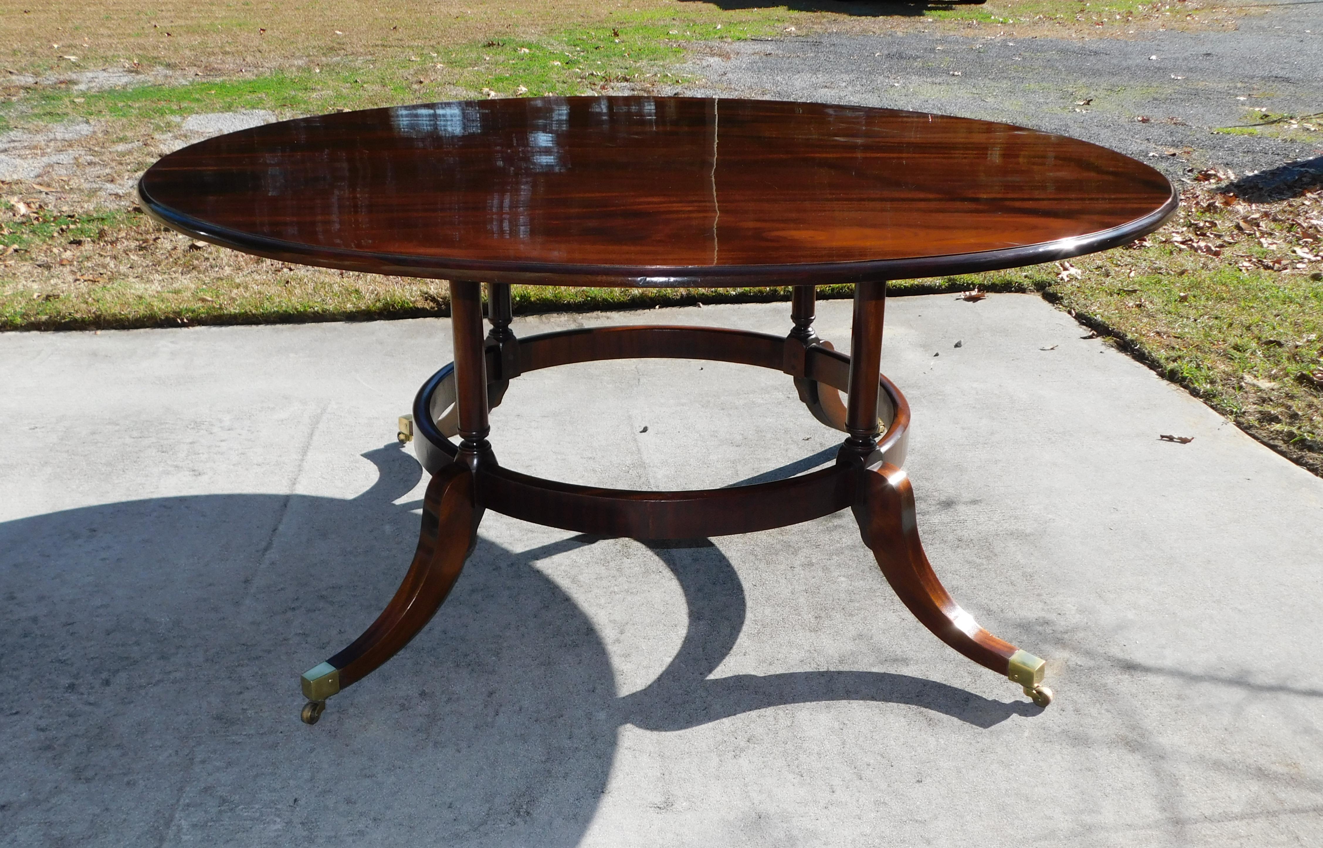 English Regency Mahogany circular dining room table with turned ringed support columns, lower circular skirt, and resting on splayed legs with the original brass casters. Mid 19th century.