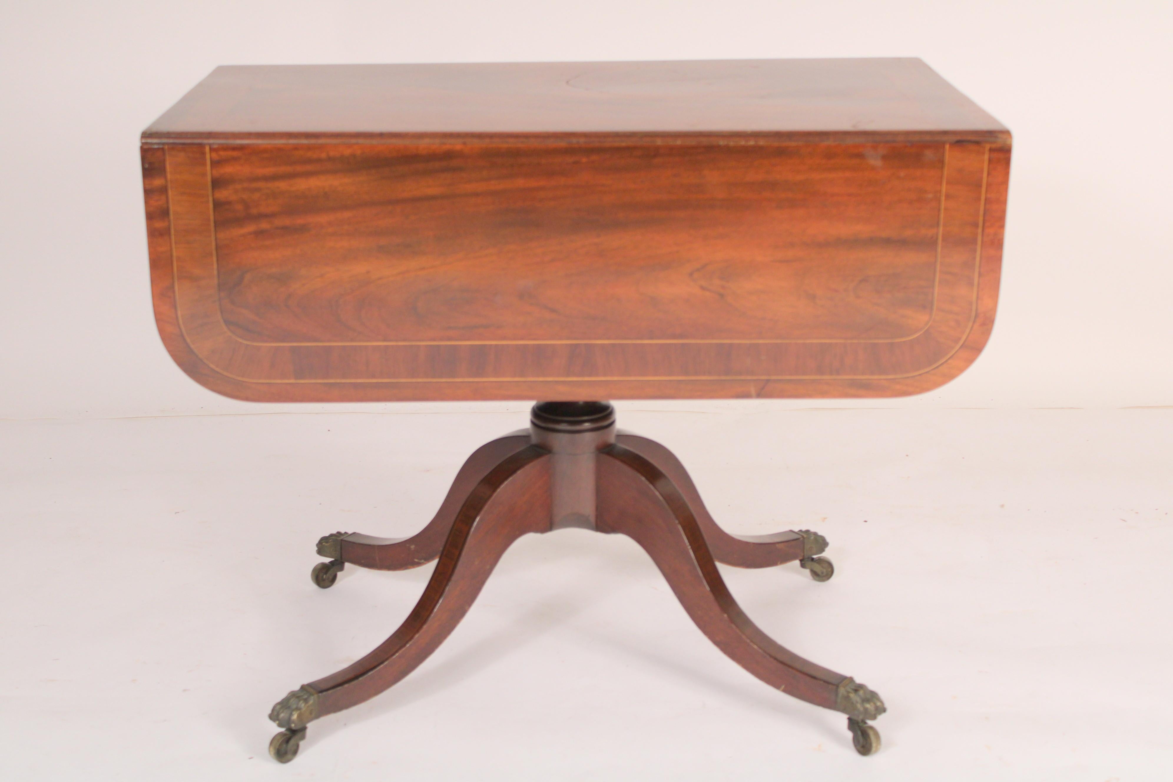 English regency mahogany drop leaf occasional table, circa 1820. An exquisite mahogany top with rosewood cross banding, frieze drawer with wood knobs, a baluster and ring turned pedestal, four down swept legs ending in brass lion paw feet on brass
