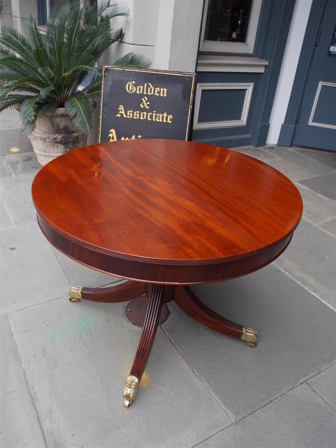 English Regency mahogany drum table with a turned bulbous ring pedestal, four reeded splayed legs, and resting on the original acanthus brass casters, early 19th century.