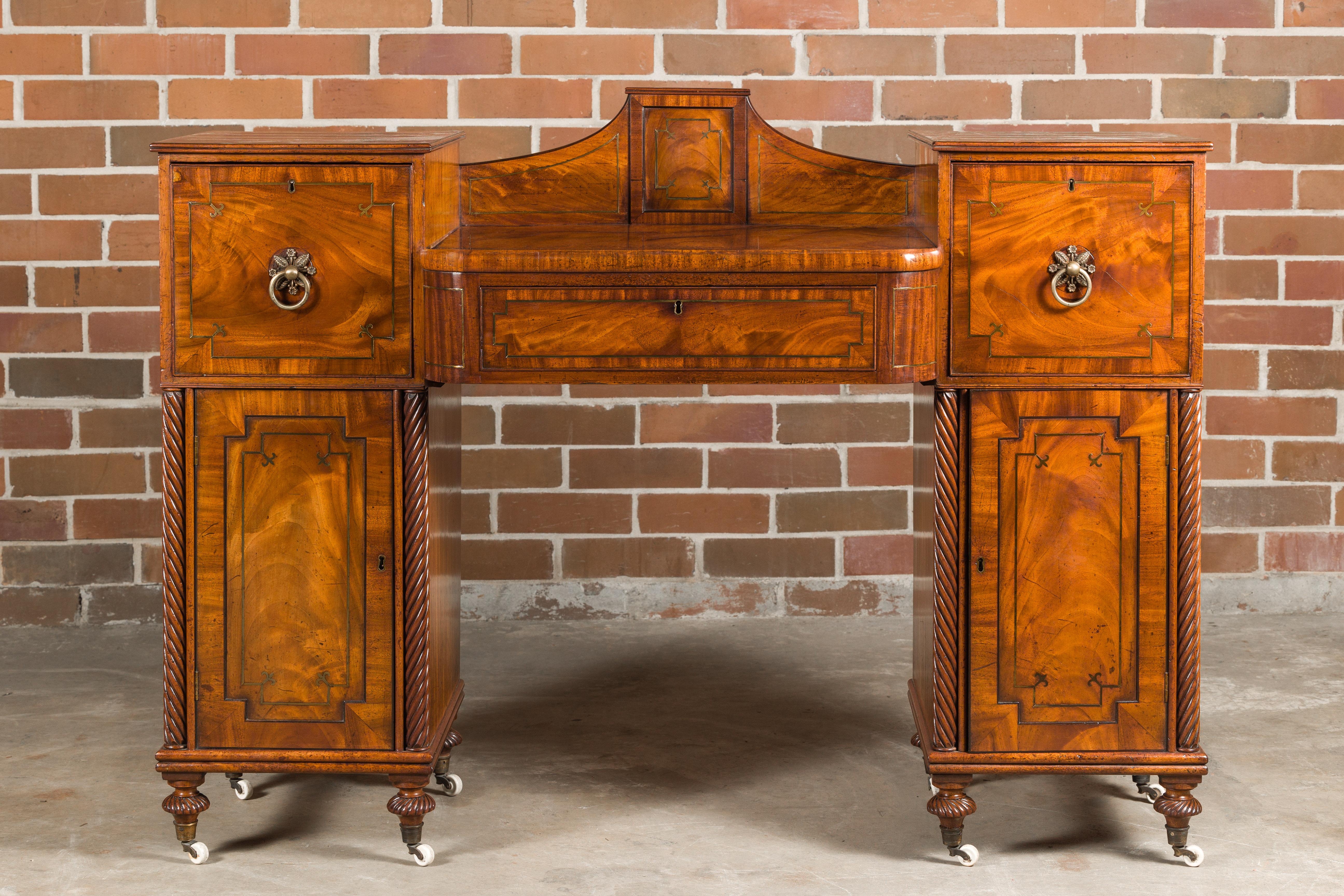 An English Regency period mahogany dressing table from the early 19th century with three drawers, two doors, brass inlay and twisted columns. Emanating an air of early 19th-century elegance, this English Regency mahogany dressing table is a timeless