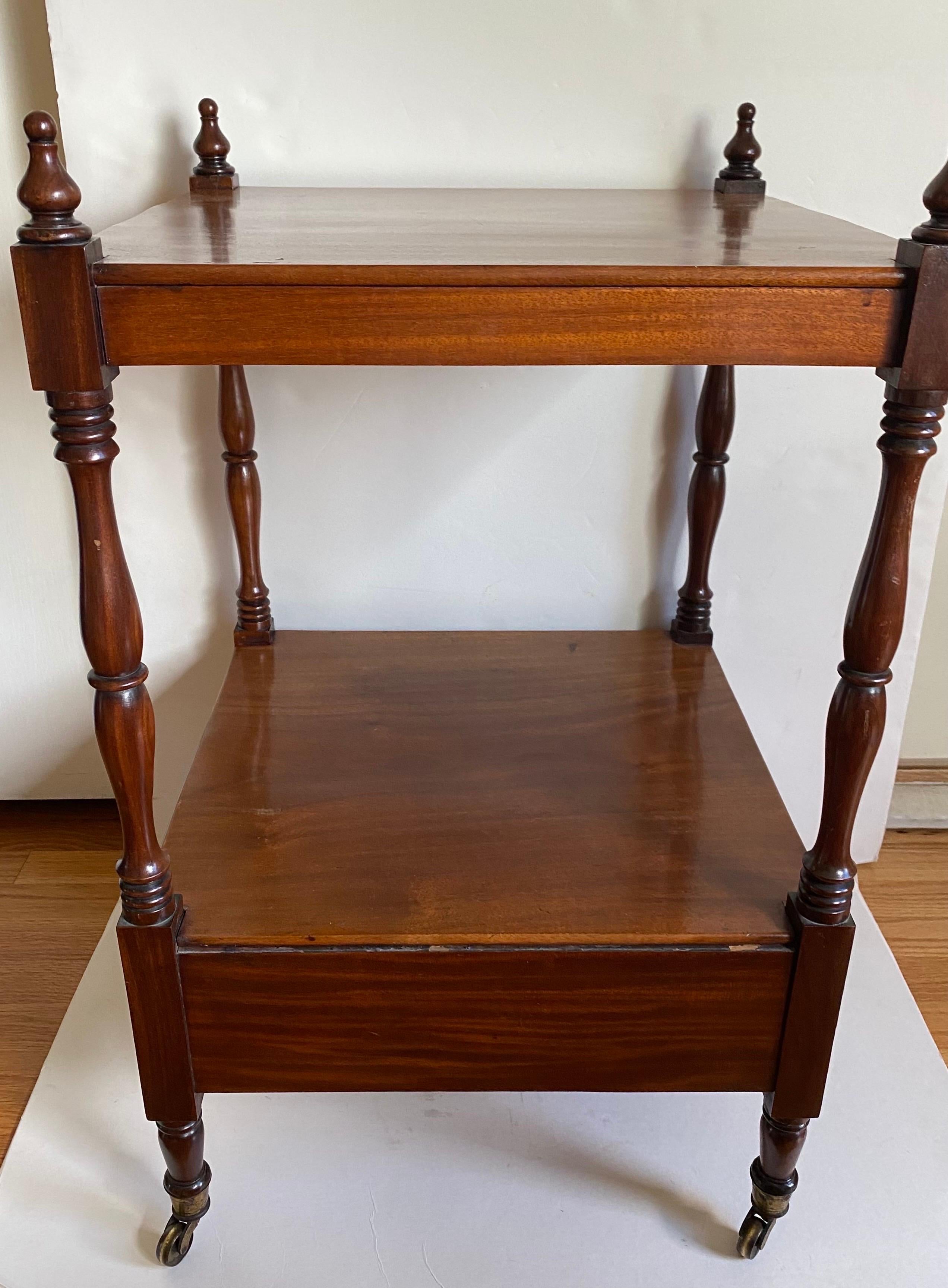Antike englische Regency-Mahagoni-Etagere oder Trolley-Tisch mit quadratischer Platte, unterer Ablage, einer Schublade, fertiger Rückseite, gedrechselten Stützen und Beinen, die in Messingrollen enden.

Englisch, um 1820 / 1830.

Provenienz: