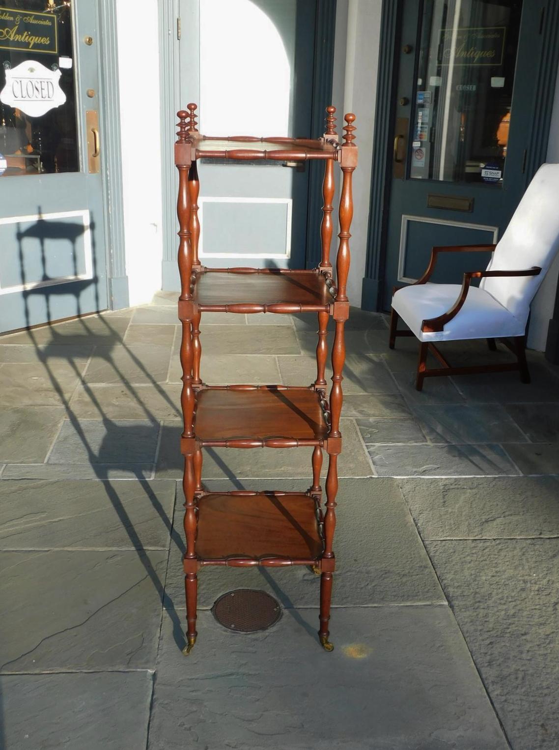 English Regency Mahogany Etagere with four squared tiers, blocked baluster ring turned bulbous supports, flanking tiered ball finials, and resting on tapered ringed legs with the original brass casters, Early 19th Century.