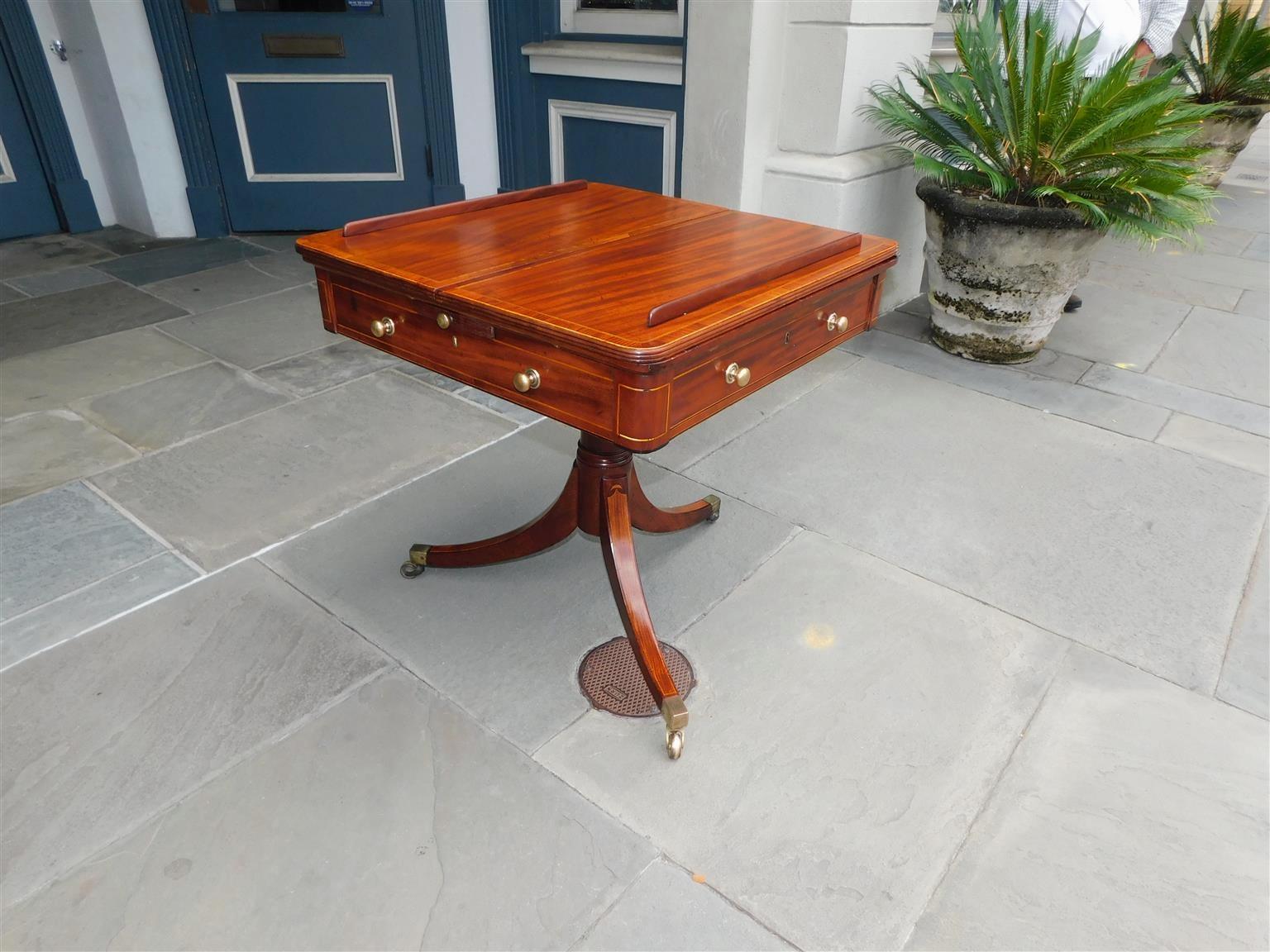 English Regency mahogany satinwood and ebony inlaid one drawer reading table with a ratcheted leather top, cross banded tulip wood, flanking candle slides with original brasses, compartmentalized fitted interior, centered ringed column, and resting