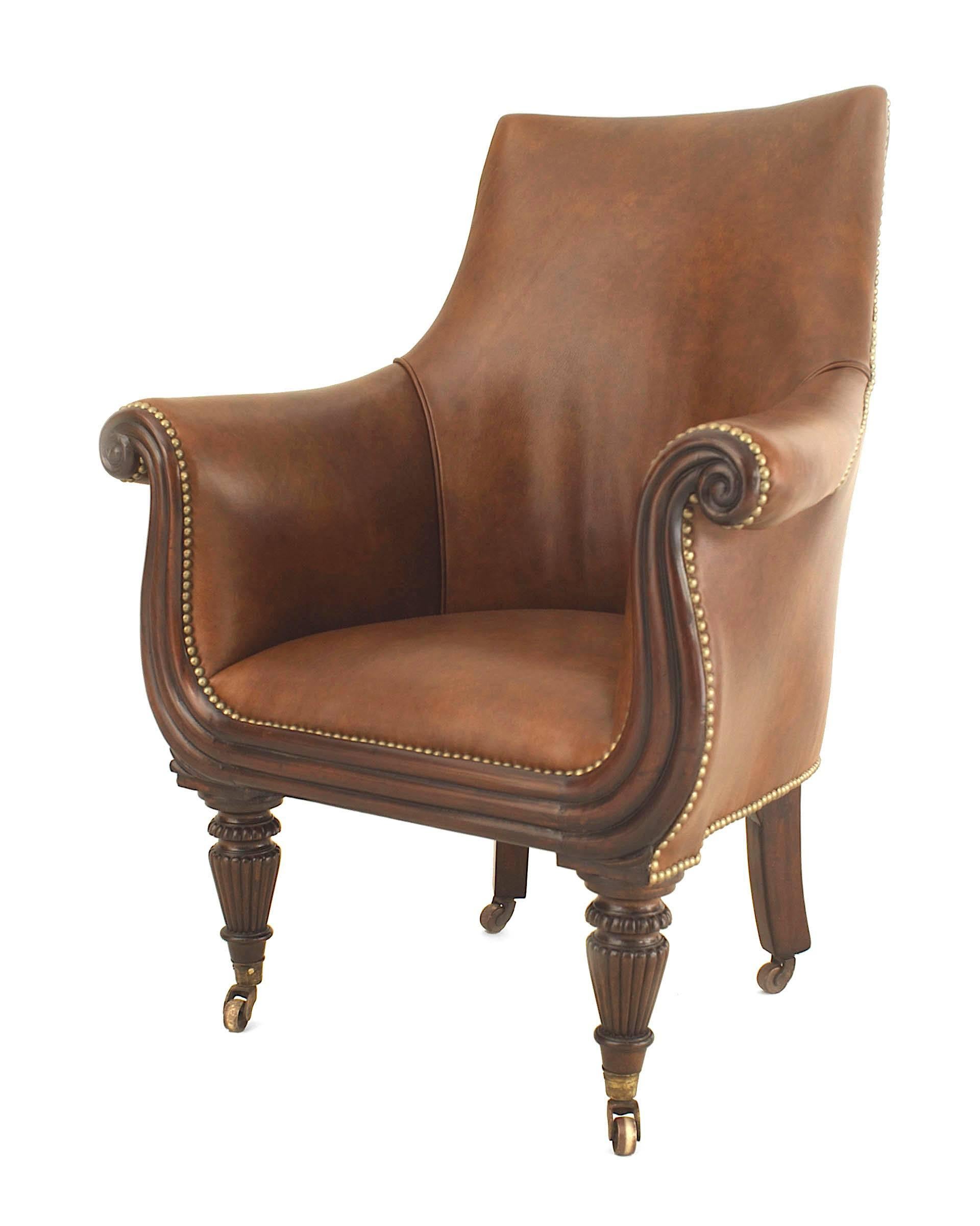 English Regency mahogany tub form library style arm chair with a brown leather upholstered seat and back having brass nail head trim.

