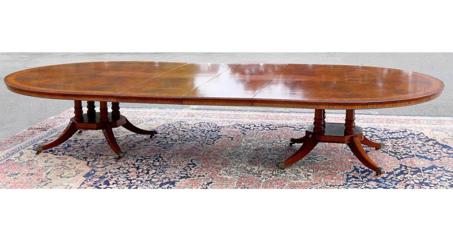 This English Regency banquet/dining table features a mahogany composition and satinwood inlaid top. The table has an extendable feature, allowing it to effortlessly adapt to various dining needs. The legs, complete with castor wheels, makes this