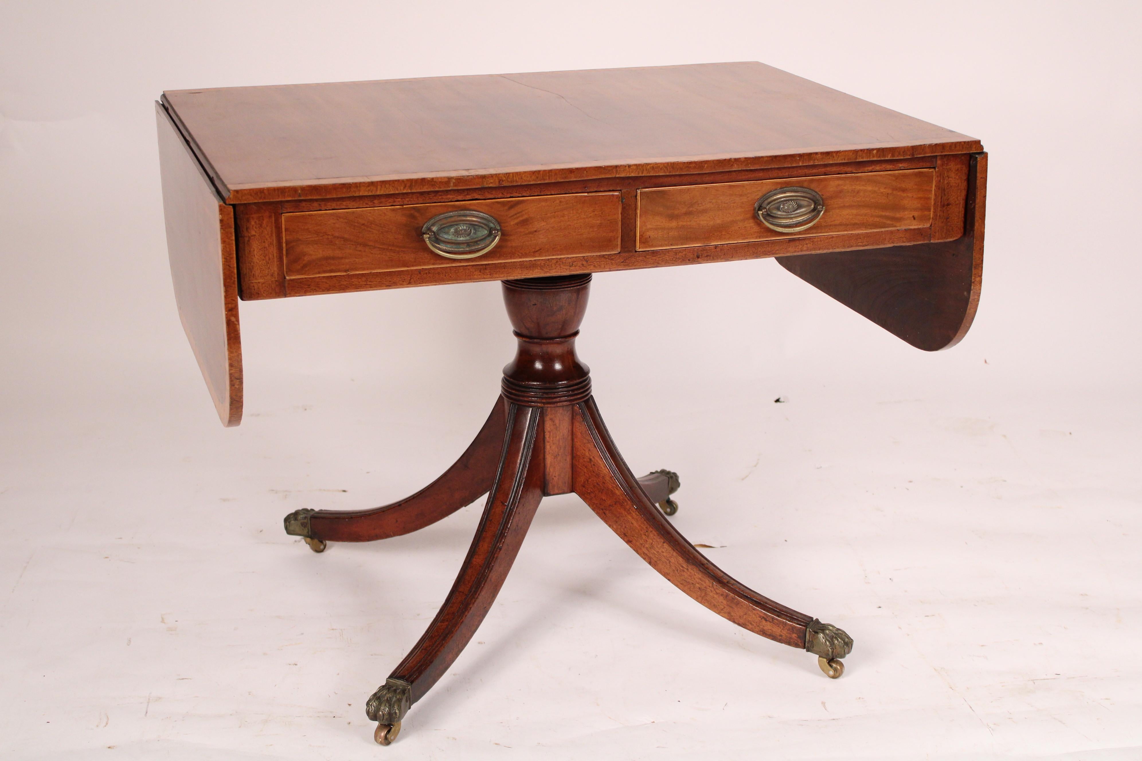 English regency mahogany sofa table, early 19th century. With a mahogany top with burl ash crossbanding and two D shaped drop leaves on either end, two frieze drawers on the front side with string inlay, the back side with string inlay, a baluster