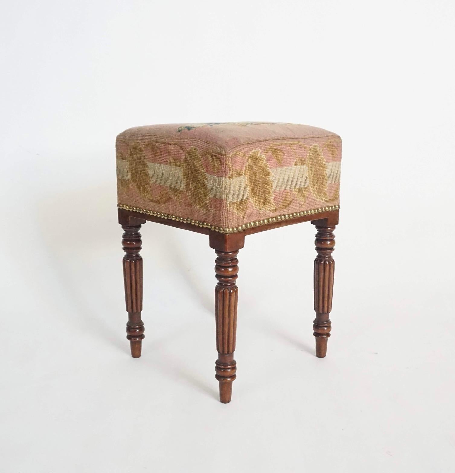 Looking quintessentially Mario Buatta is this wonderful circa 1820 English regency period mahogany stool having tall upholstered seat with original needlepoint or tapestry, the top depicting a spaniel carrying a letter in its mouth and all sides