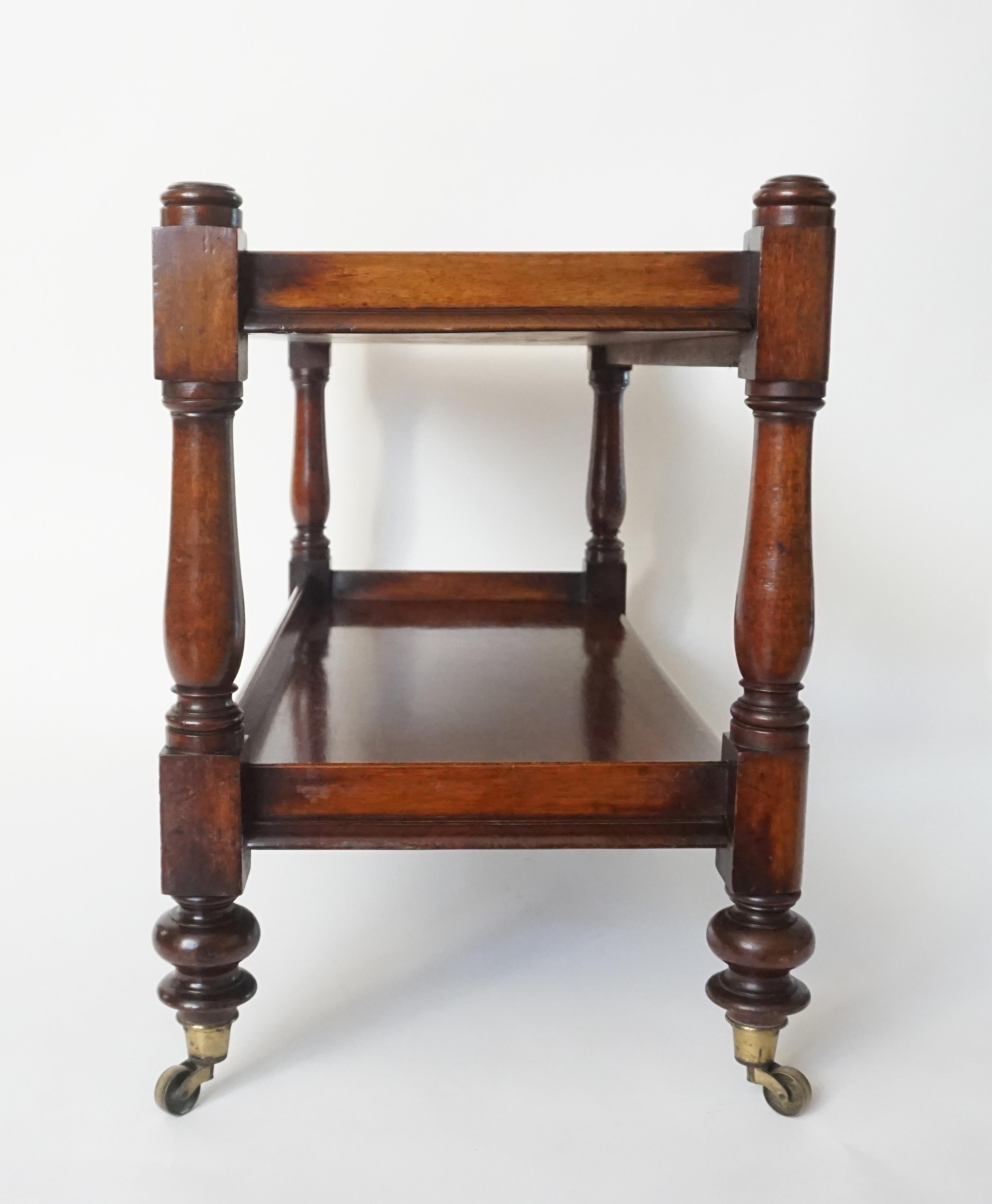 William IV English late Regency period mahogany étagère or trolley of rectangular two-tier form having turned corner stiles on original brass casters. A beautiful piece with many uses; wonderful as a coffee table or television stand to name a