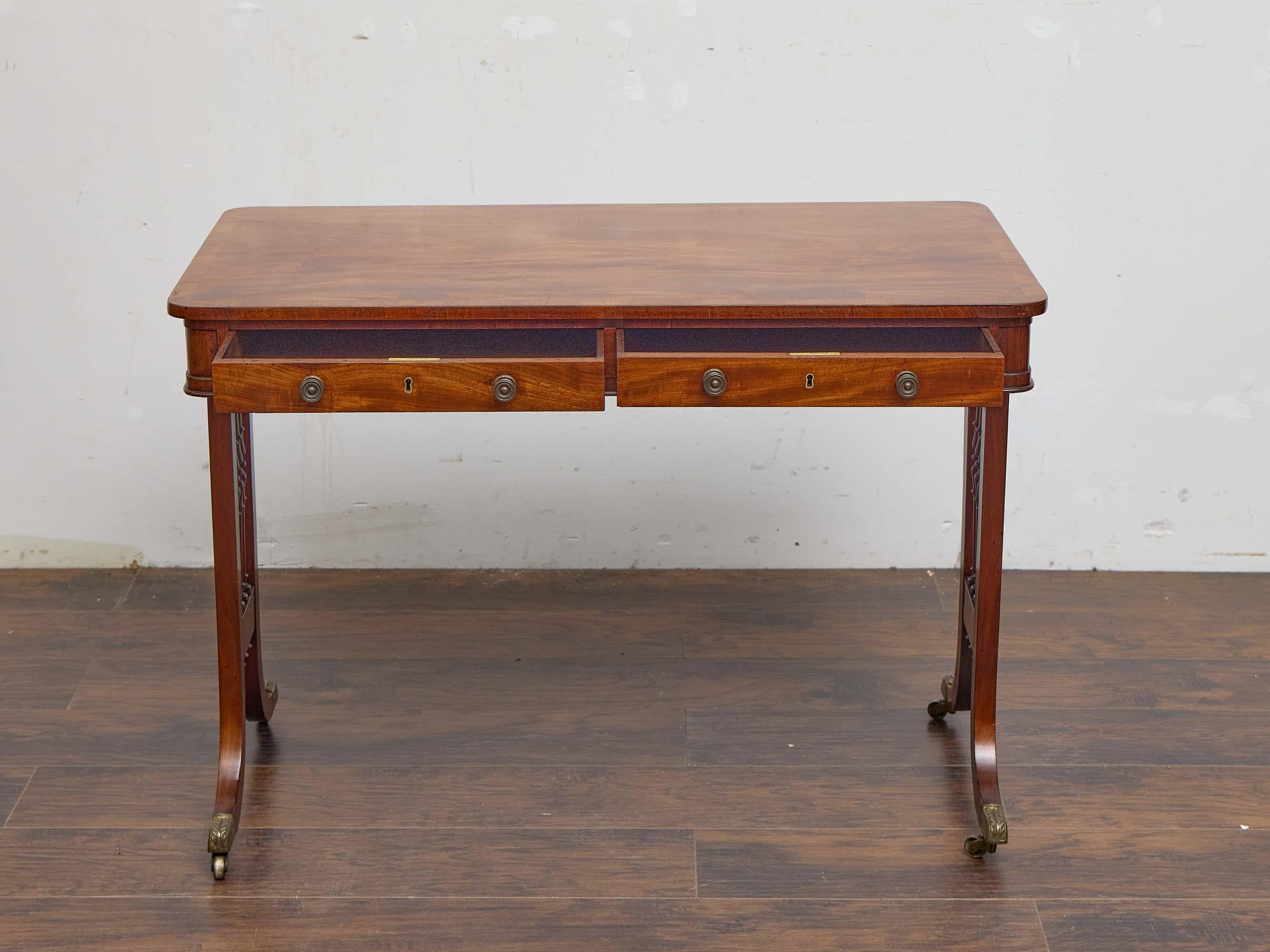 This early 19th-century English Regency writing desk exemplifies the refined elegance of the period through its restrained silhouette, balanced proportions, and decorative details. The rectangular top is constructed in mahogany with a beautifully