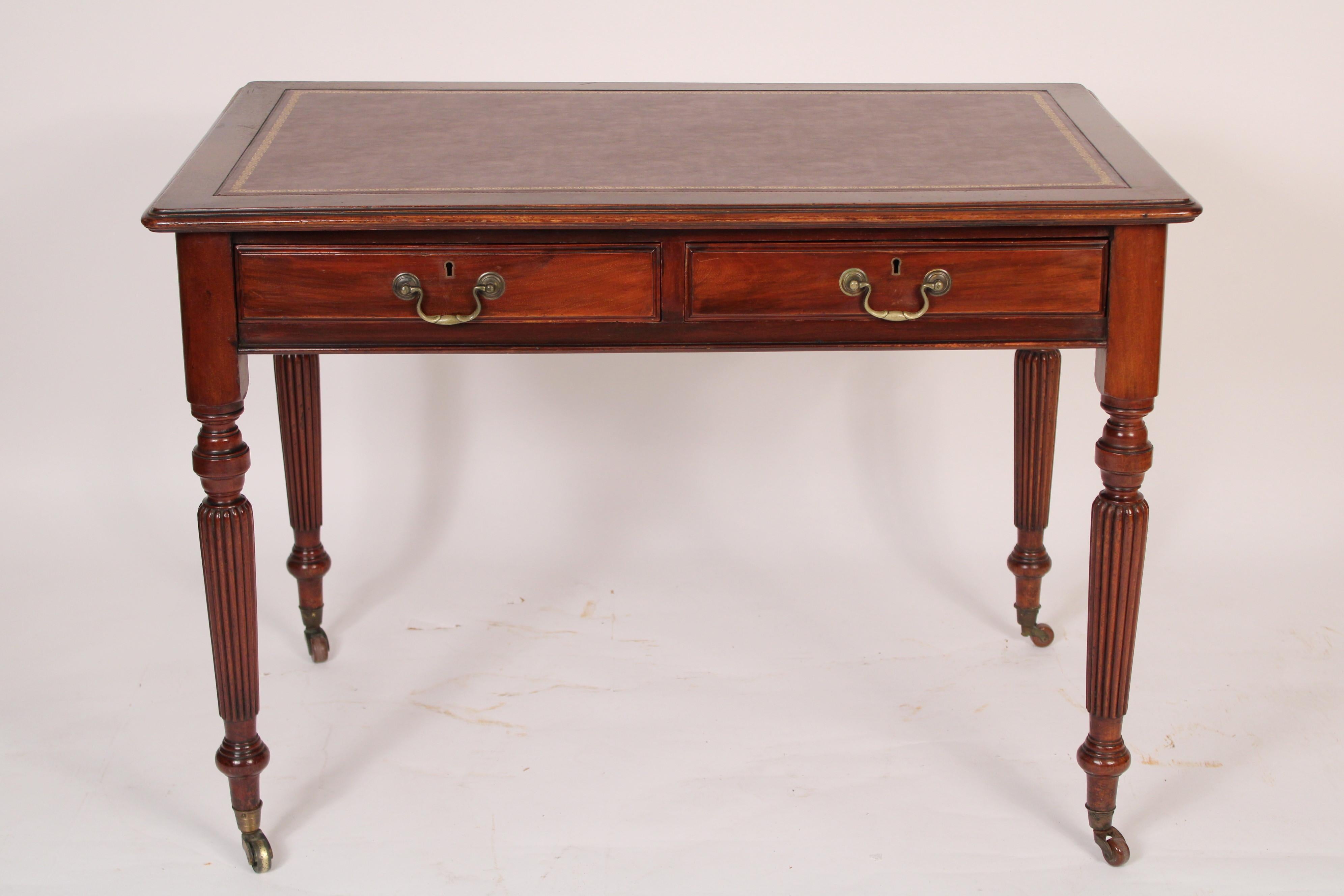 English regency mahogany writing table, 19th century. With a tooled leather top, two frieze drawers with lever locks, four tapered reeded legs ending in brass casters. Hand dove tailed drawer construction. Knee clearance 23.25