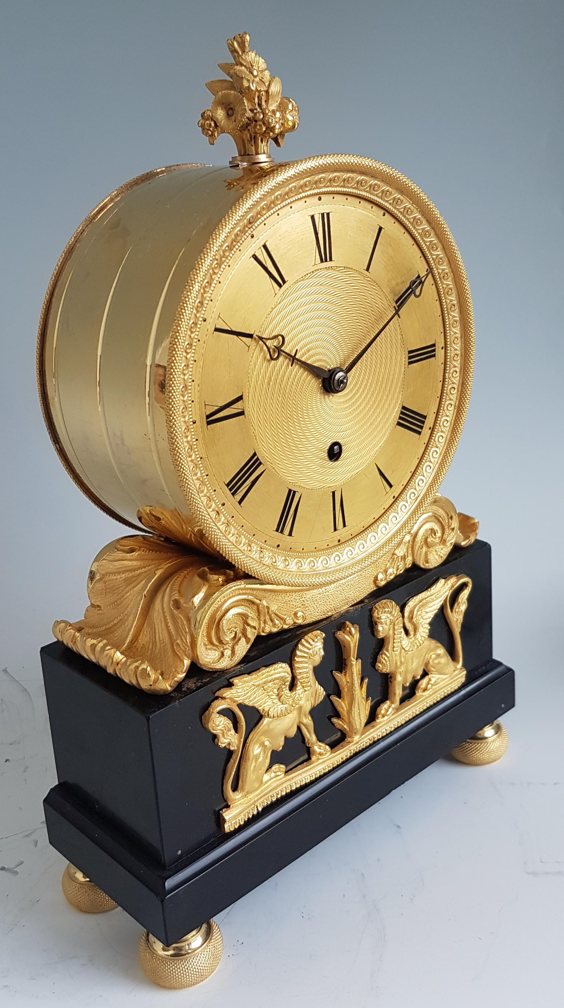 A very fine antique English Regency ormolu and black marble mantel timepiece with eight day movement. The superb circular ormolu dial with engine turned decoration with swirling decoration to the centre, roman numerals and blued steel heart shaped