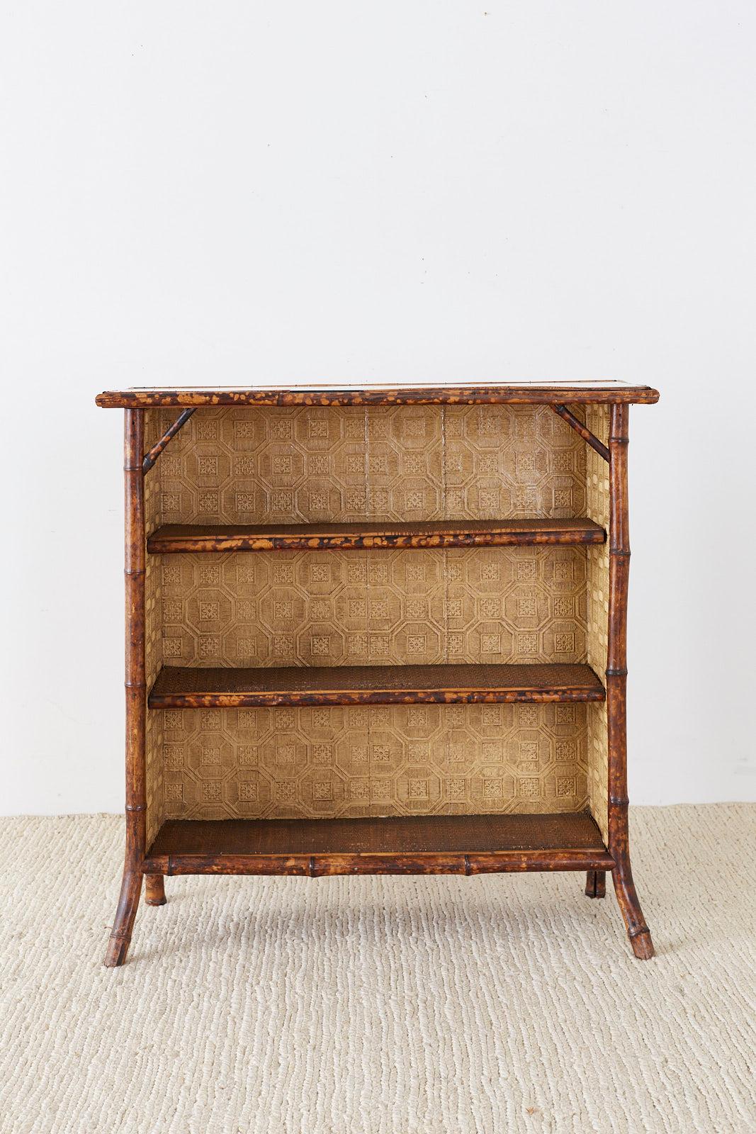 Attractive English Regency style bamboo bookcase or shelf featuring a later mirrored frame. Constructed from thick bamboo poles with a rich tortoise finish having a three shelf interior covered with raffia grasscloth. Excellent joinery with later