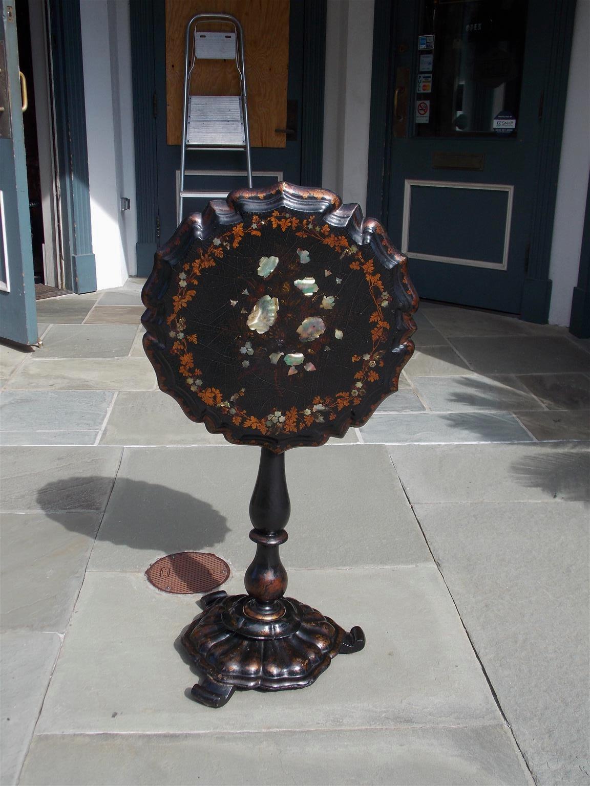 English Regency papier mâché tilt top scalloped edge tea table with gilt stenciled foliage motif, mother of pearl inlays, turned bulbous ringed pedestal, original locking mechanism, and resting on a circular gadrooned base with three scrolled feet.
